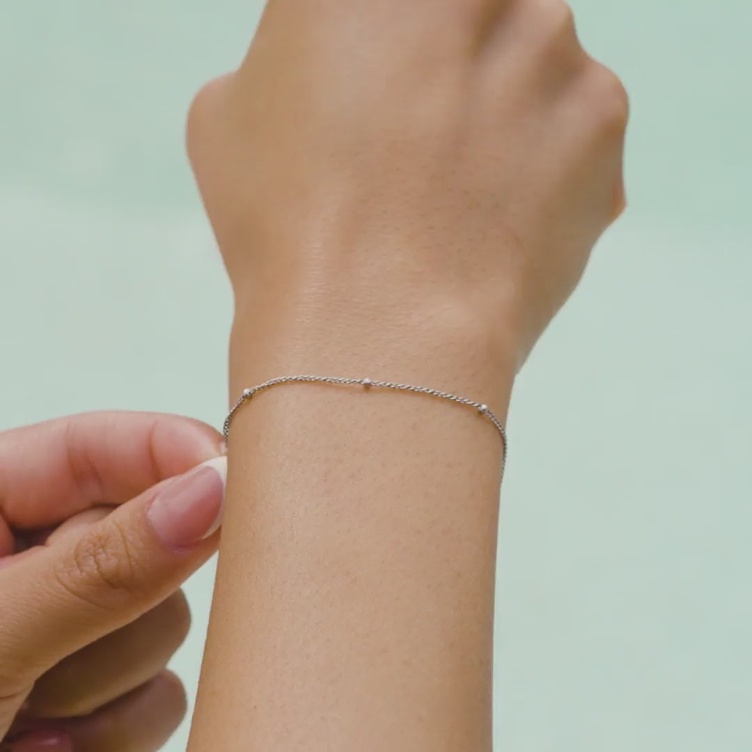 video of a dainty stainless steel satellite chain bracelet on a model at the pool