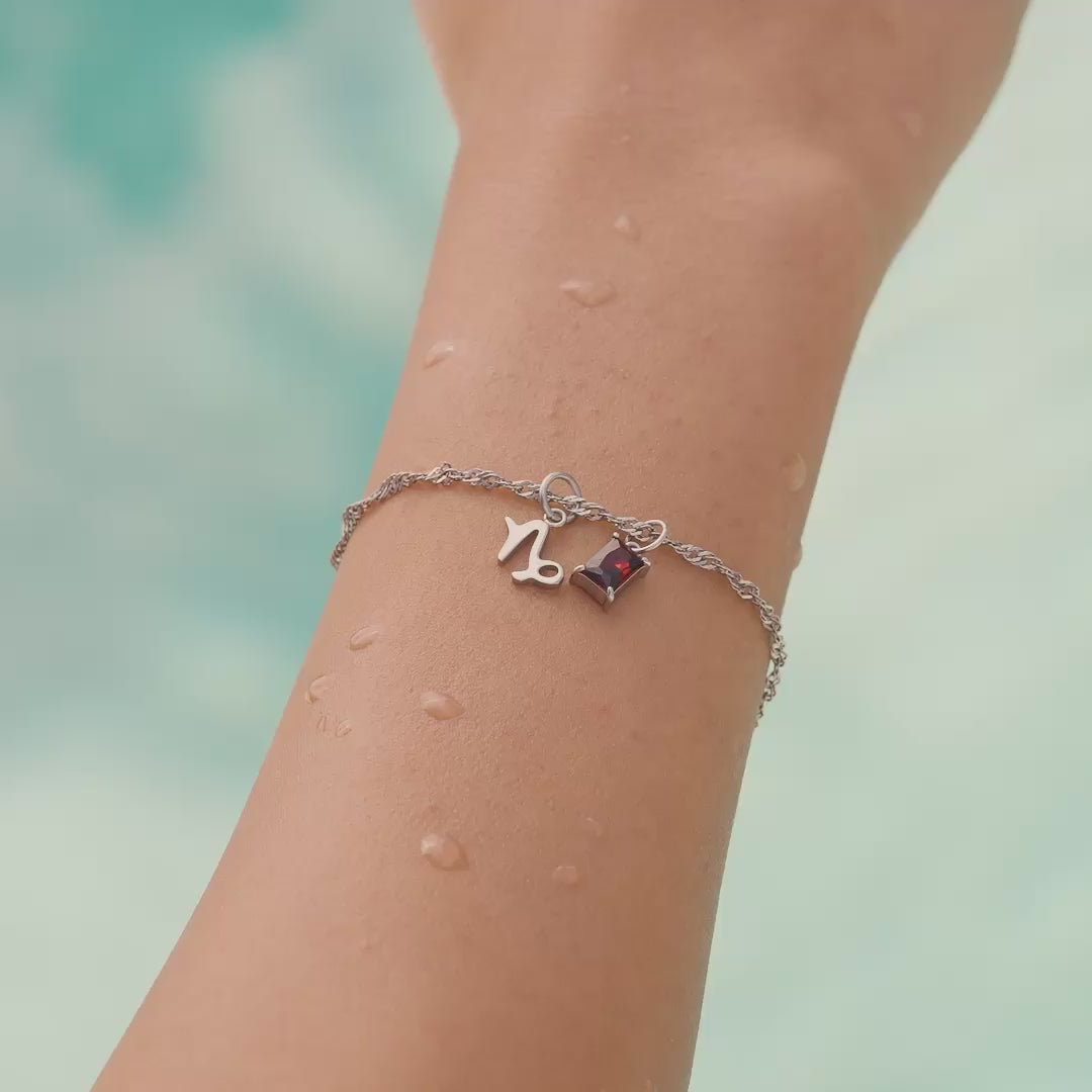 a video of all 12 zodiac charms shown in silver stainless steel in both flatlay form as well as worn by a model