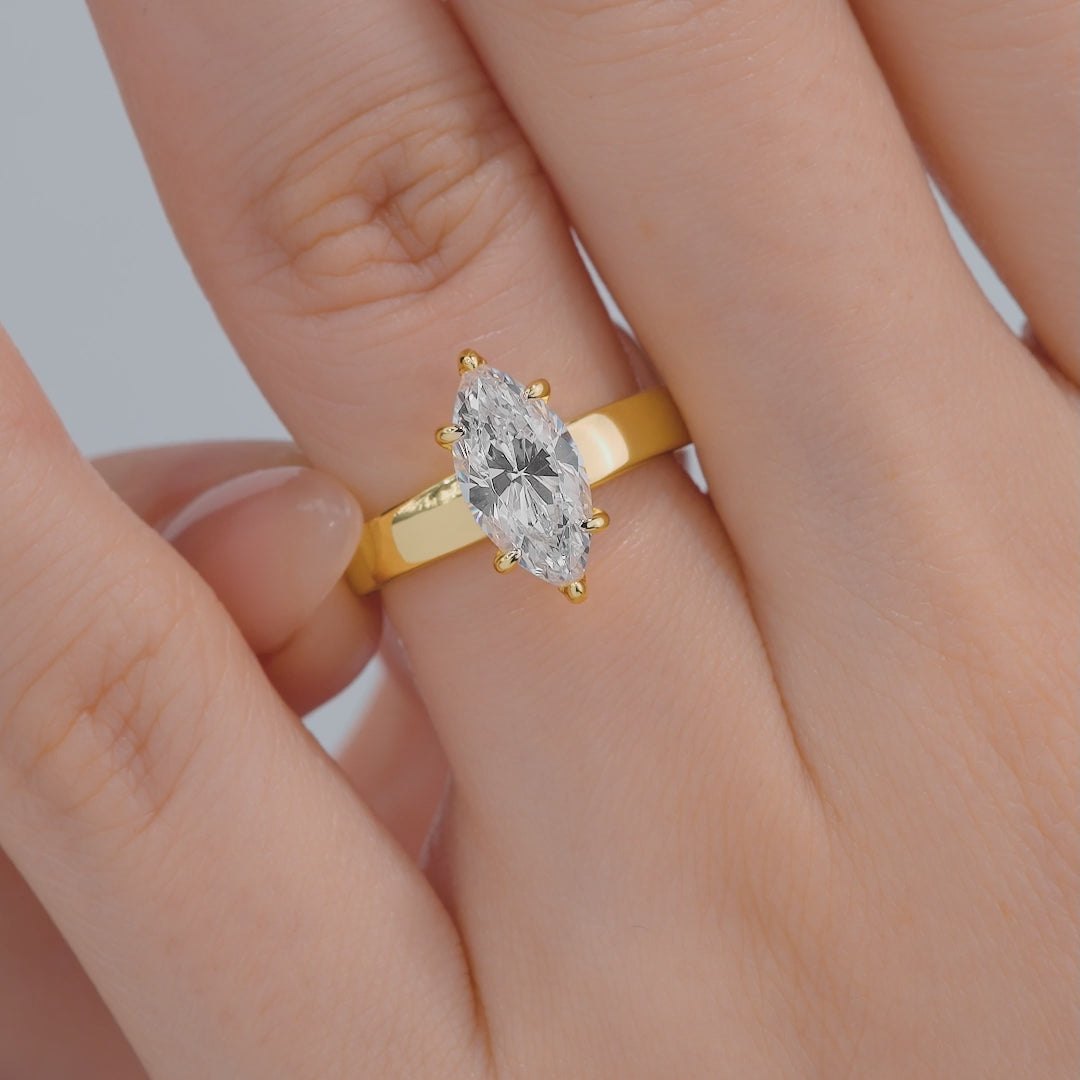 video of a thick, gold 2 carat marquise cut solitaire engagement ring on model