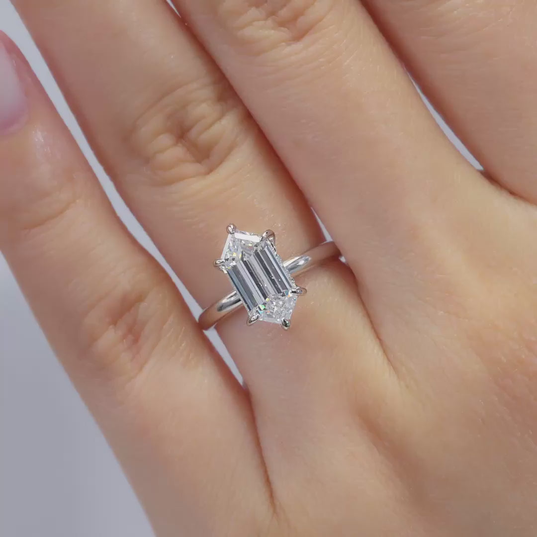 a video of a silver 2.5 carat hexagon cut solitaire hidden halo solitaire engagement ring worn by a model, shown in multiple poses