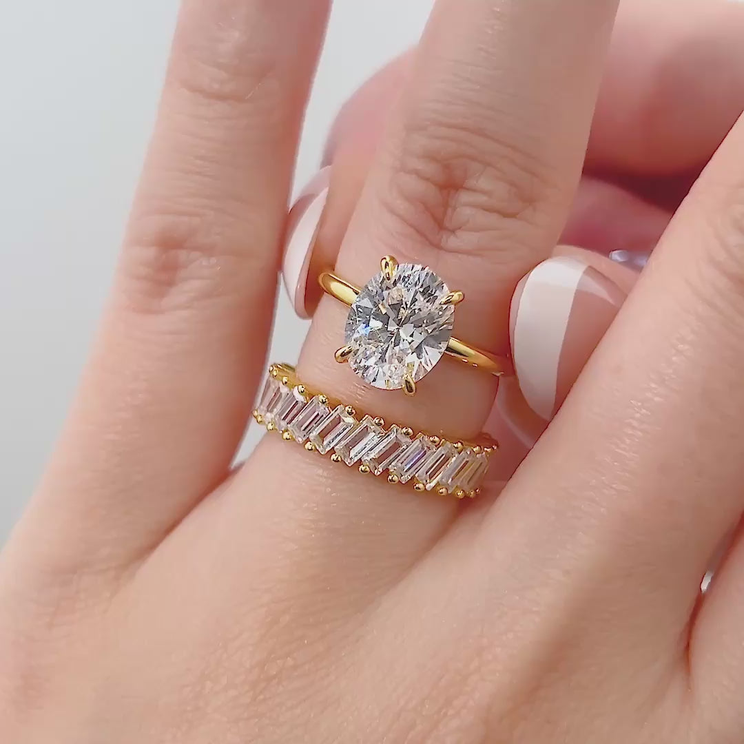 video of gold 3 carat oval cut solitaire and baguette band wedding ring set on model with french tip nails