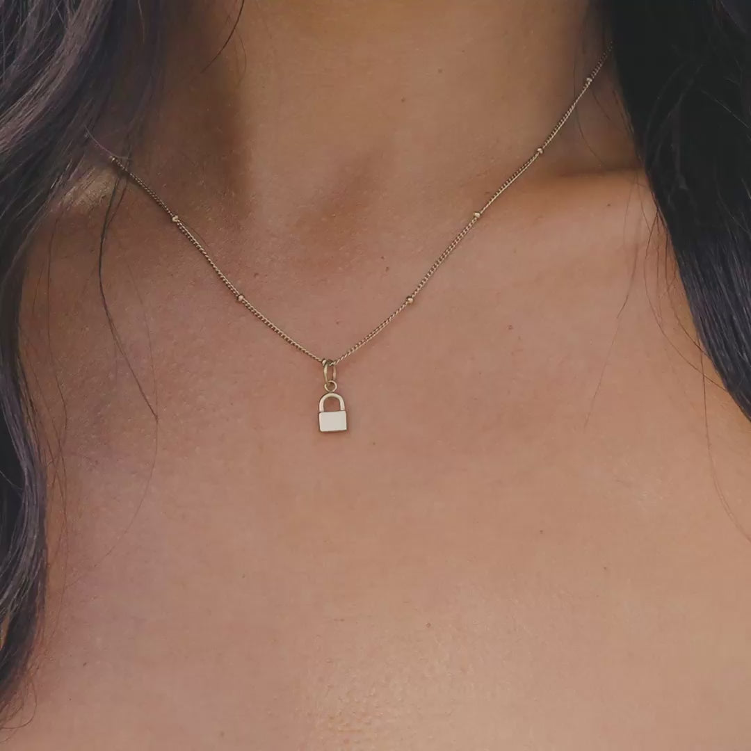 Gold Stainless Steel Lock Charm worn on a satellite chain on a model