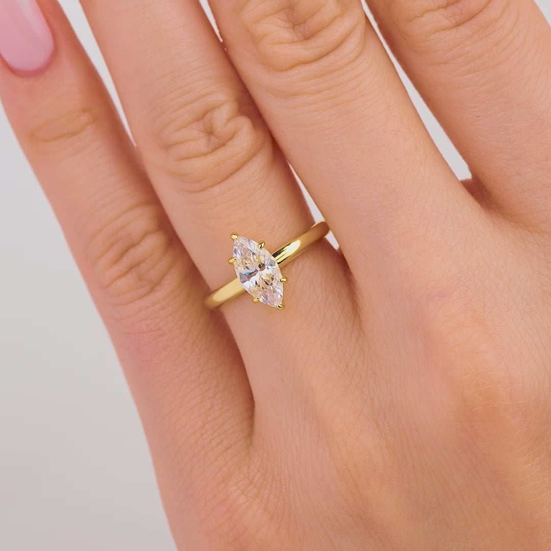 Video of petite gold marquise cut solitaire ring on model with light pink nails