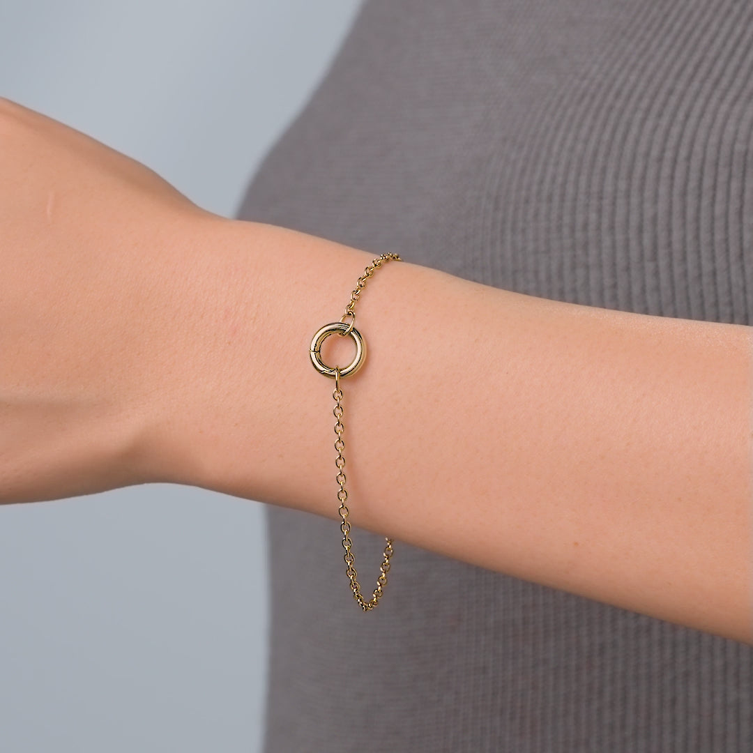 video of a dainty gold stainless steel cable chain charm bracelet on a female model