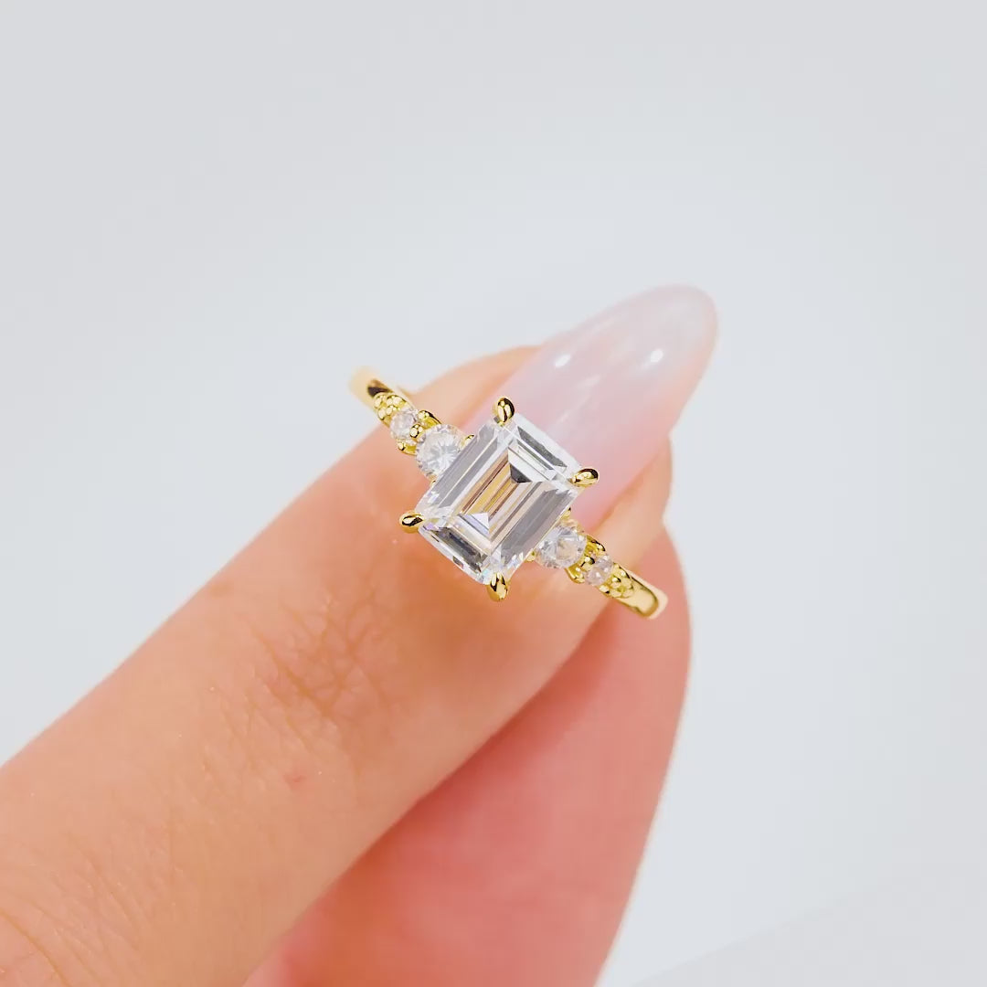 video of stunning gold 1.5 carat emerald cut engagement ring worn by model with neutral nails