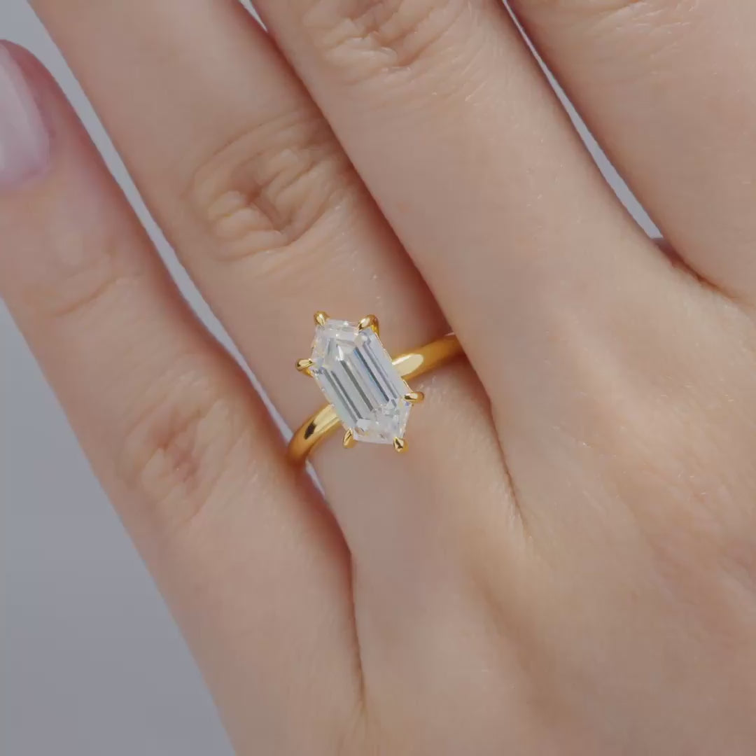 a video of a gold 2.5 carat hexagon cut solitaire hidden halo solitaire engagement ring worn by a model, shown in multiple poses