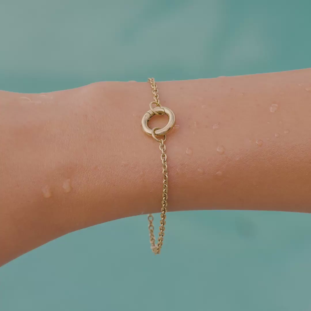 video of a 14k gold PVD plated stainless steel charm bracelet on a model by the pool