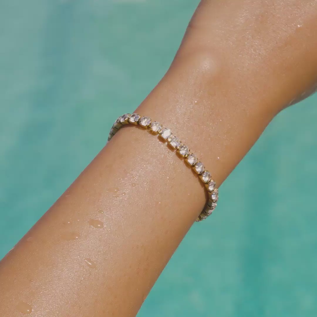 video of a stunning, waterproof, 14k gold PVD plated stainless steel tennis bracelet on a model by the pool