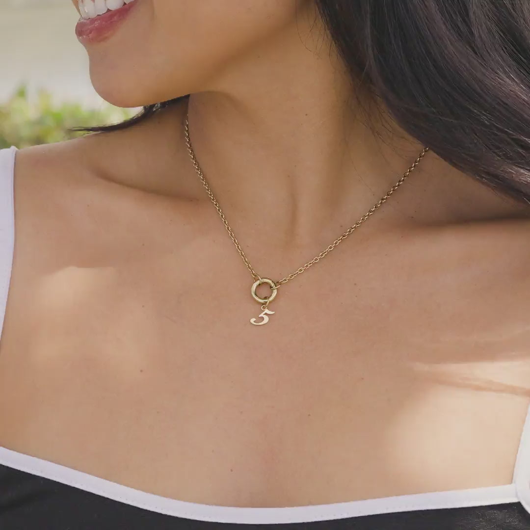 Gold stainless steel charm necklace with gold number charm "5" worn by model