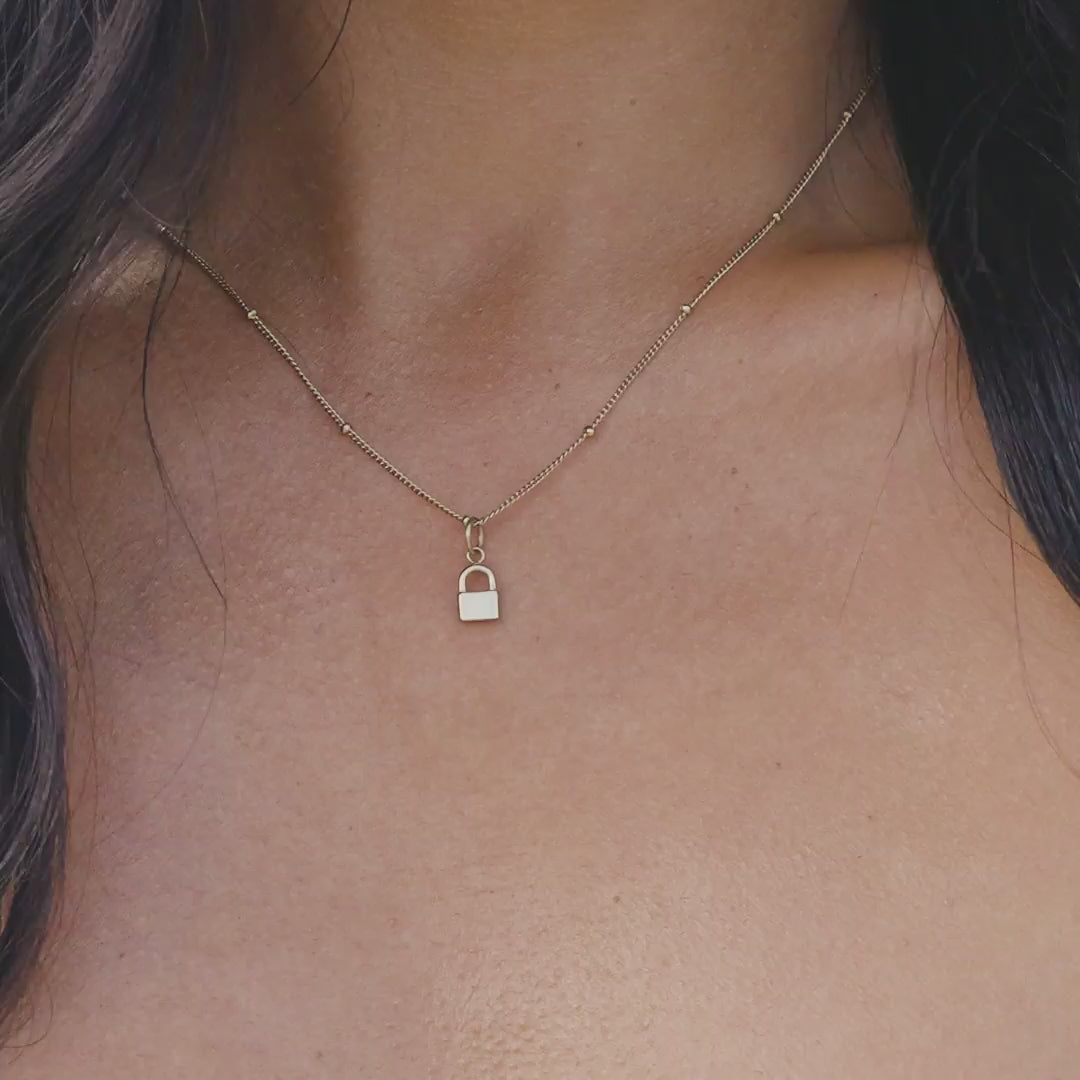 Gold Stainless Steel Lock Charm worn on a satellite chain on a model