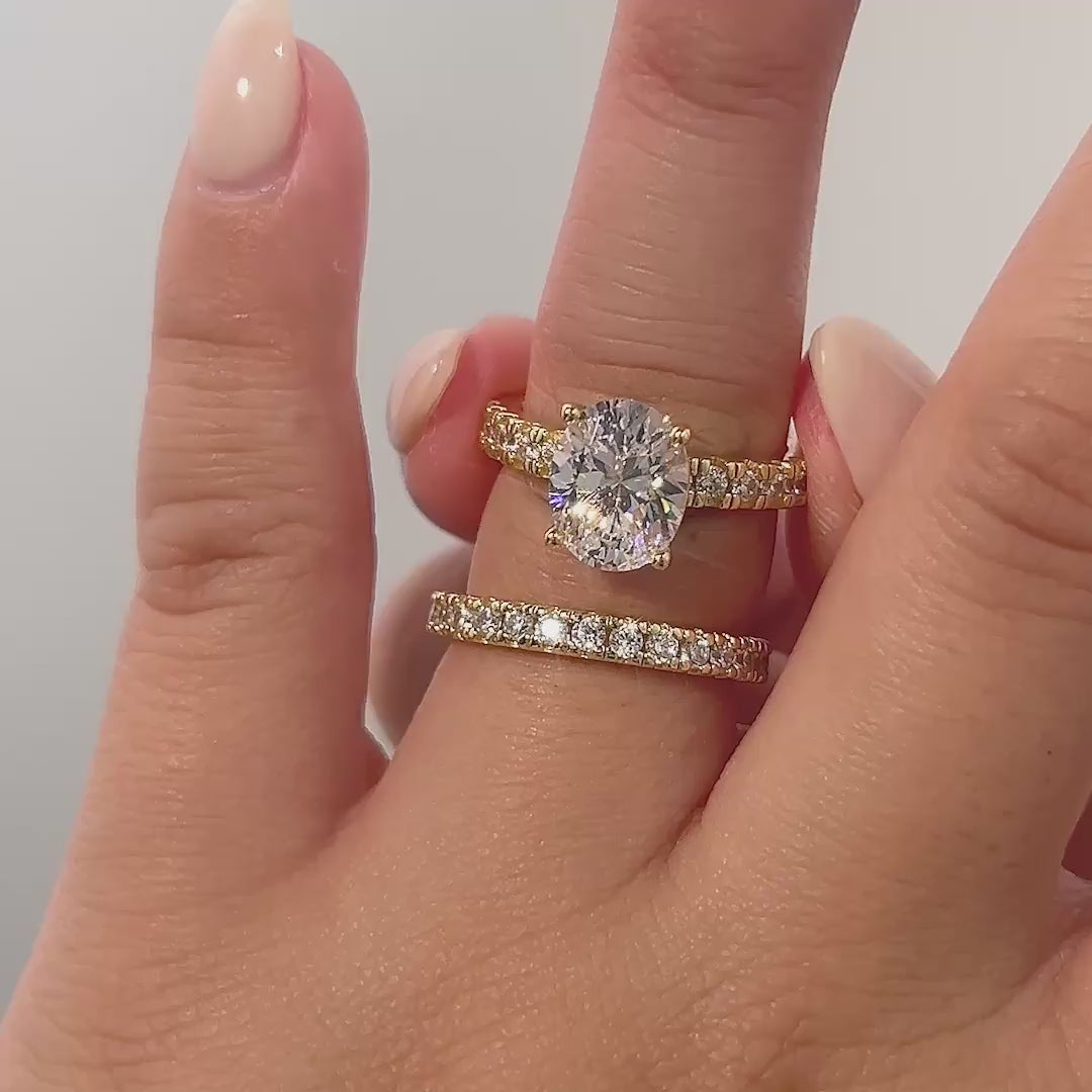 video of gold oval cut wedding ring set on model with neutral nails
