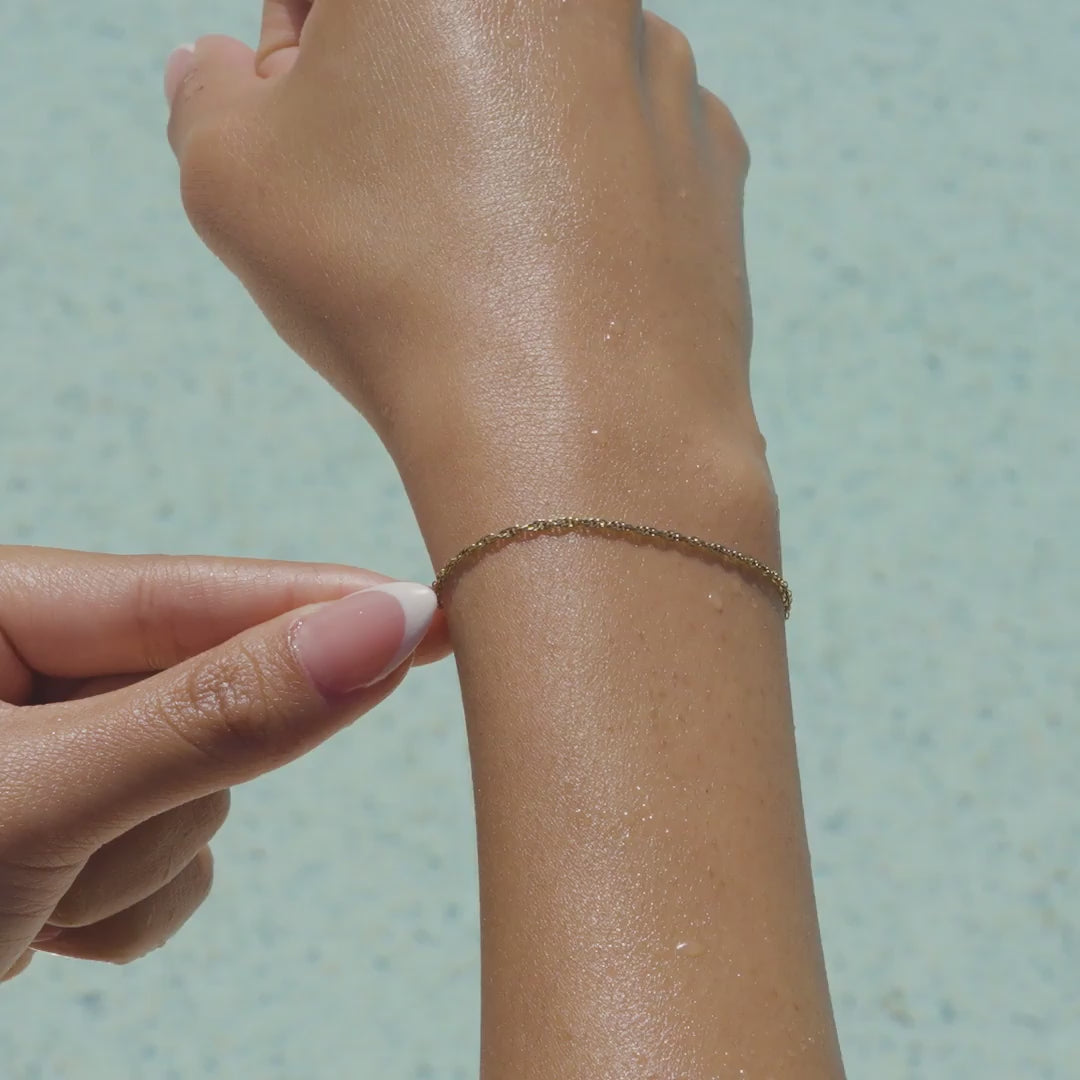 video of a 14k gold PVD plated stainless steel twisted detail cable chain bracelet on a model by the pool