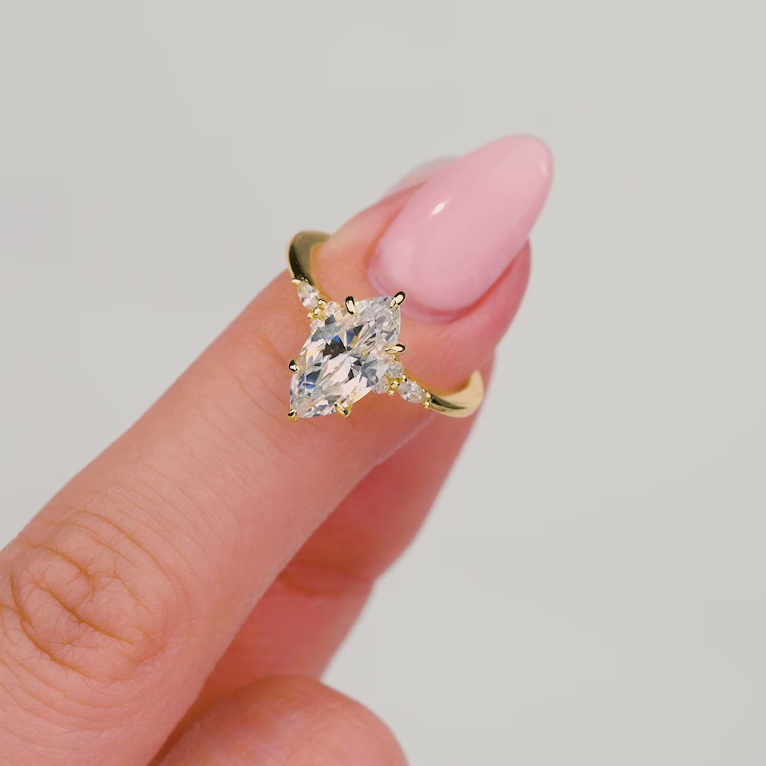 video showcasing a woman wearing a gold marquise engagement ring with intricate stones surrounding it