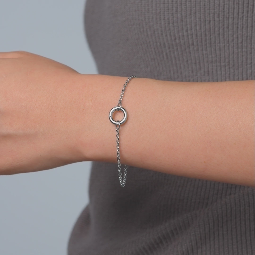 video of a dainty silver stainless steel cable chain charm bracelet on a female model