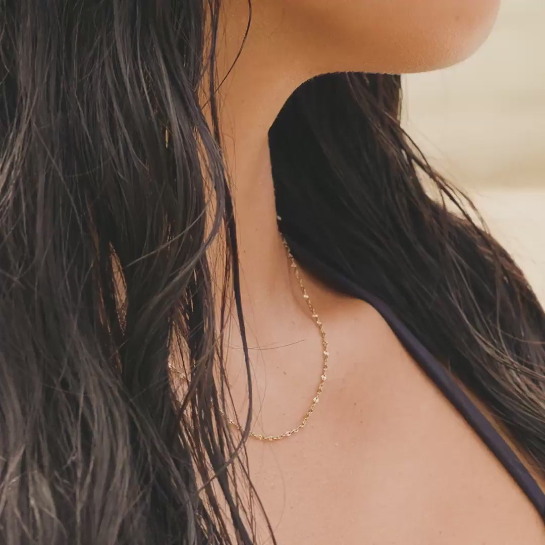 video of a dainty 14k gold pvd plated stainless steel diamond cut lip chain necklace on a model with dark hair