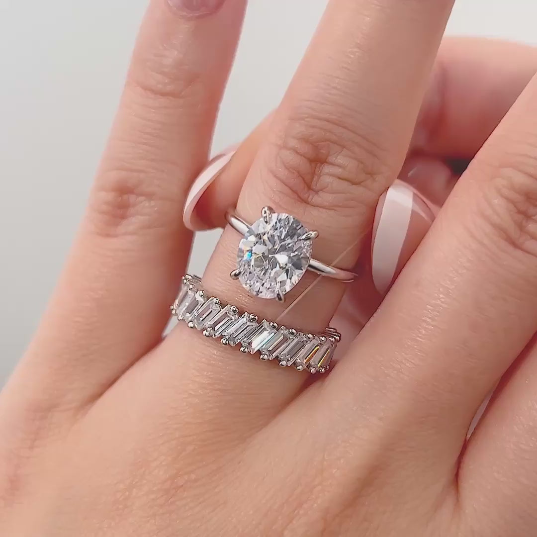 video of silver 3 carat oval cut solitaire and baguette band wedding ring set on model with french tip nails