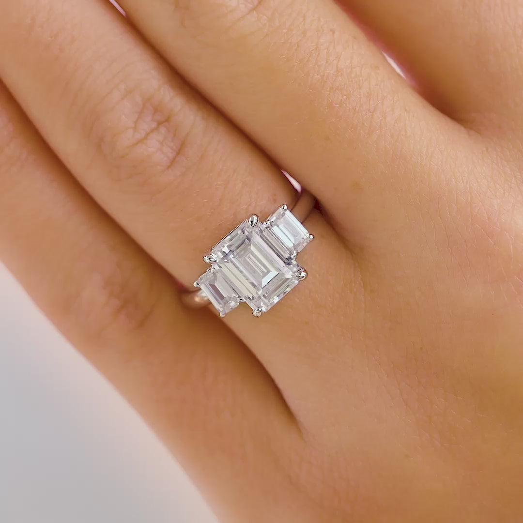 video of a stunning emerald cut trio engagement ring on model's hand