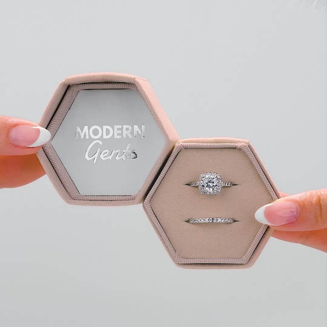 A video of velvet material hexagon shaped ring box with Modern Gents logo inside of the lid, shown in colors: stone, taupe, and black. Held by female model with french tip nails.