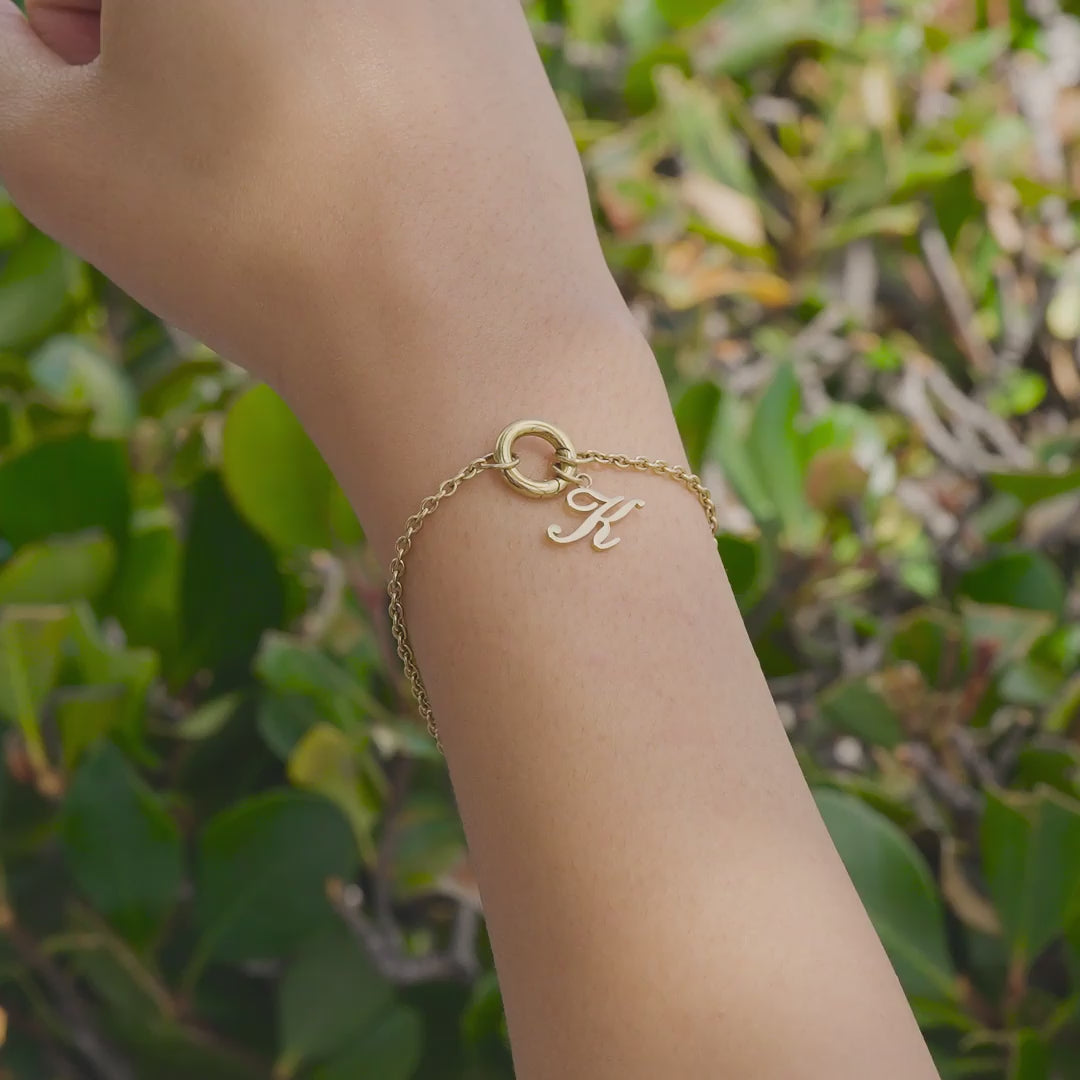 Gold Stainless Steel Charm Bracelet with Gold Initial Charm in "K" worn by model who is outside