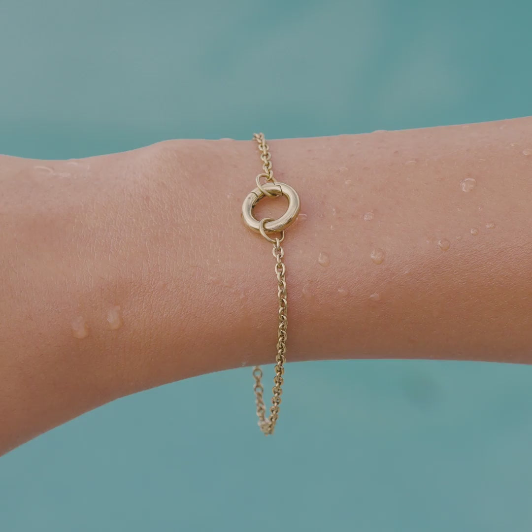 video of a 14k gold PVD plated stainless steel charm bracelet on a model by the pool