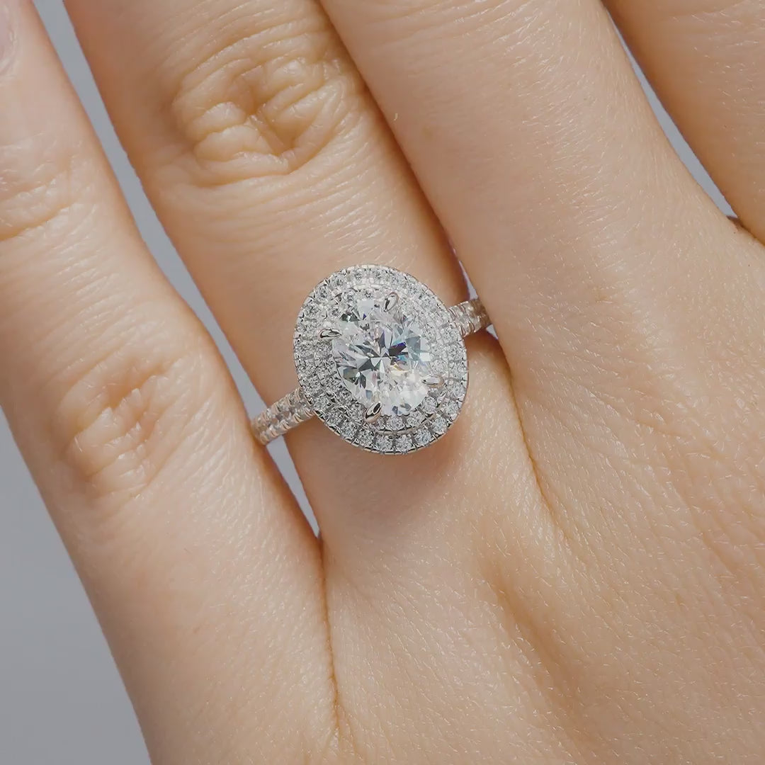 silver 1.5 carat oval cut double halo engagement ring being modeled by a model with neutral nails