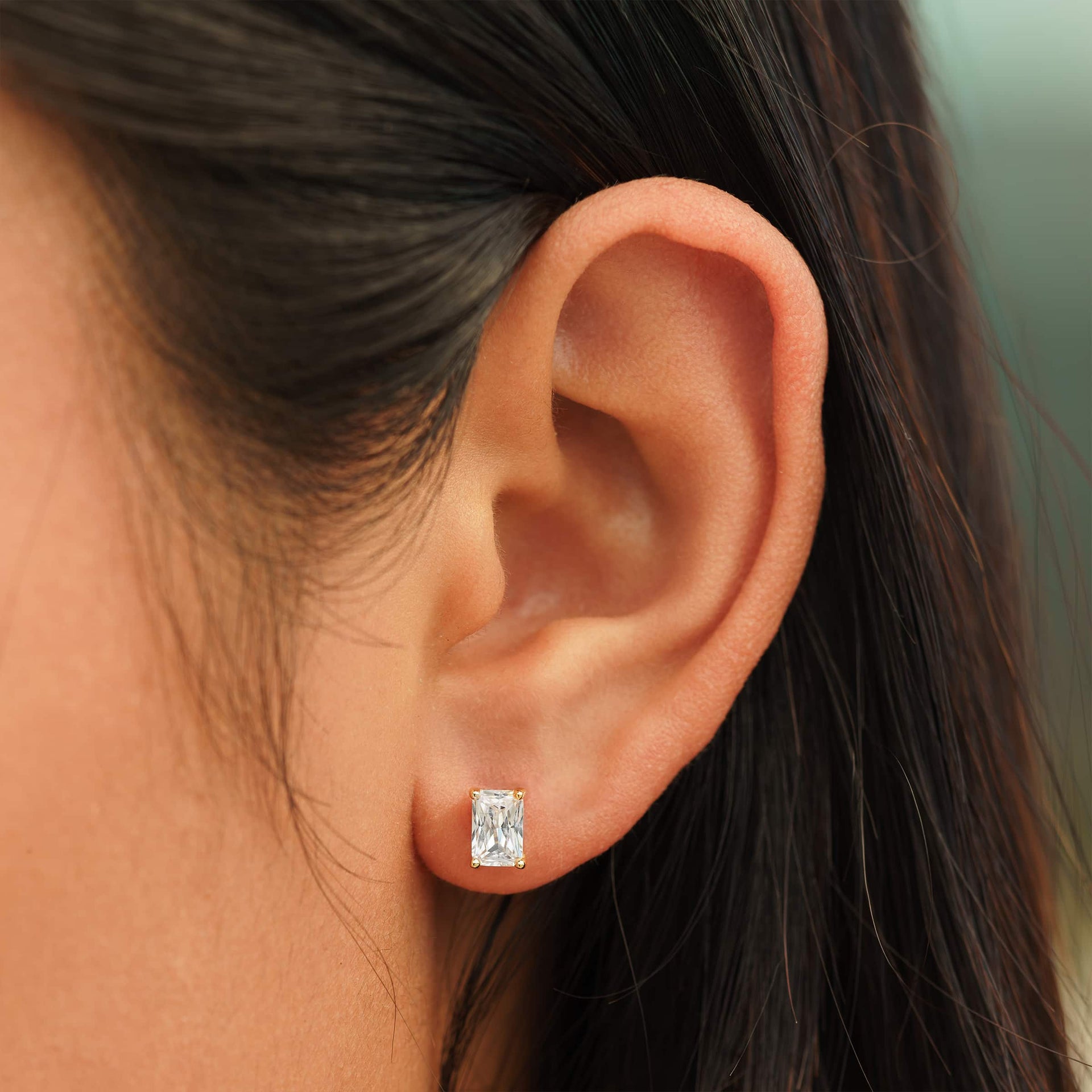 small gold radiant cut stud earrings on female model