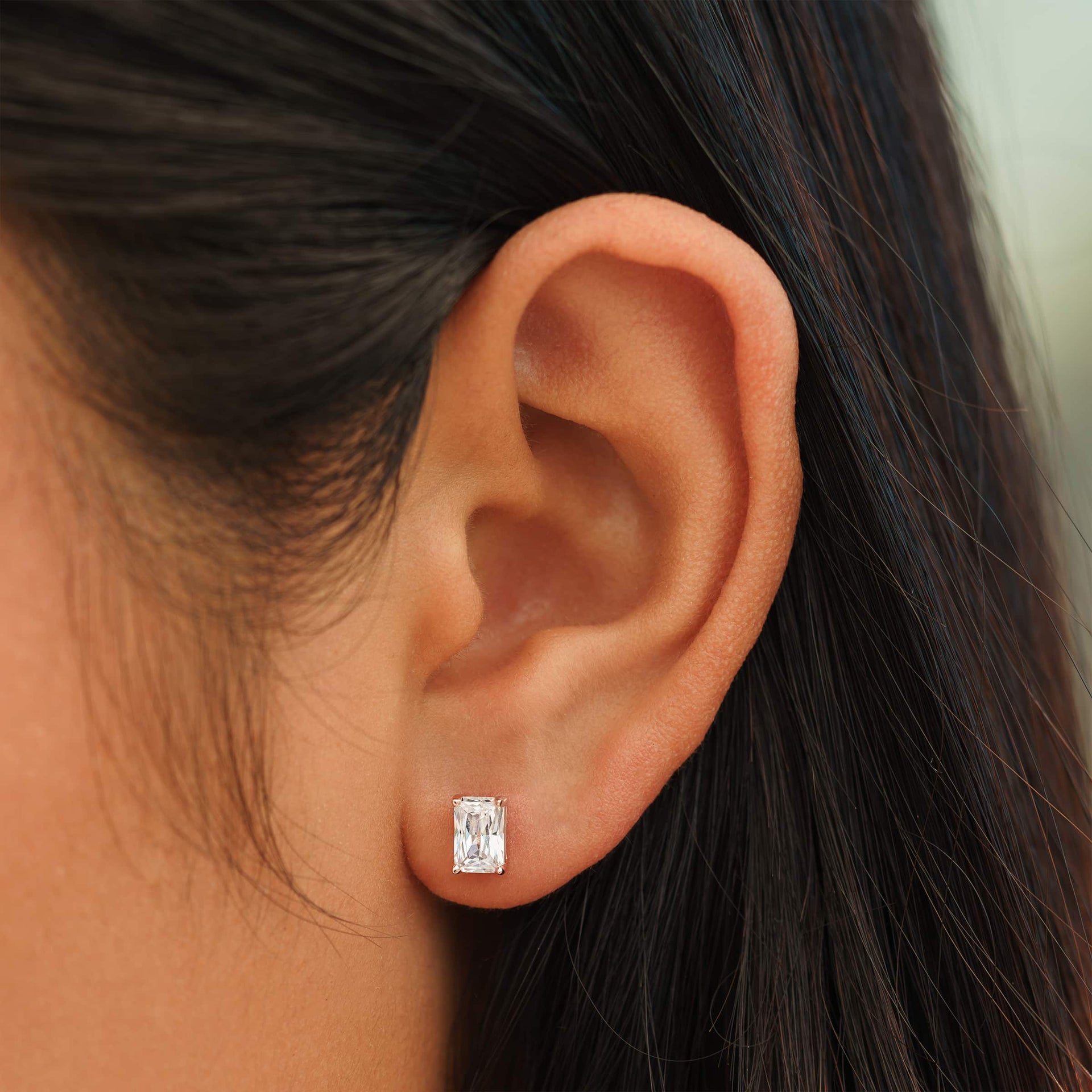 small rose gold radiant cut stud earrings on female model