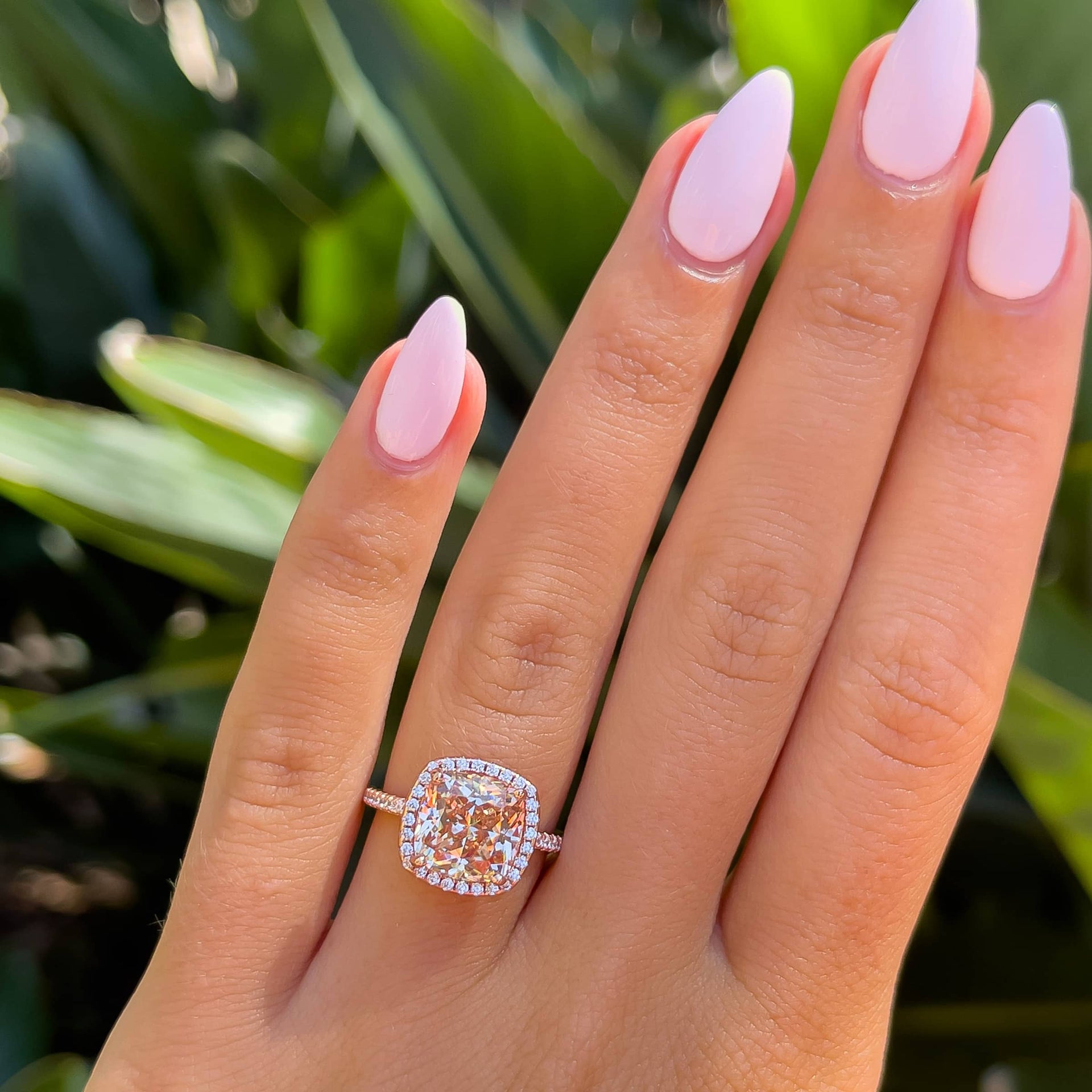 vibrant simulated morganite rose gold halo engagement ring on model with light pink nails