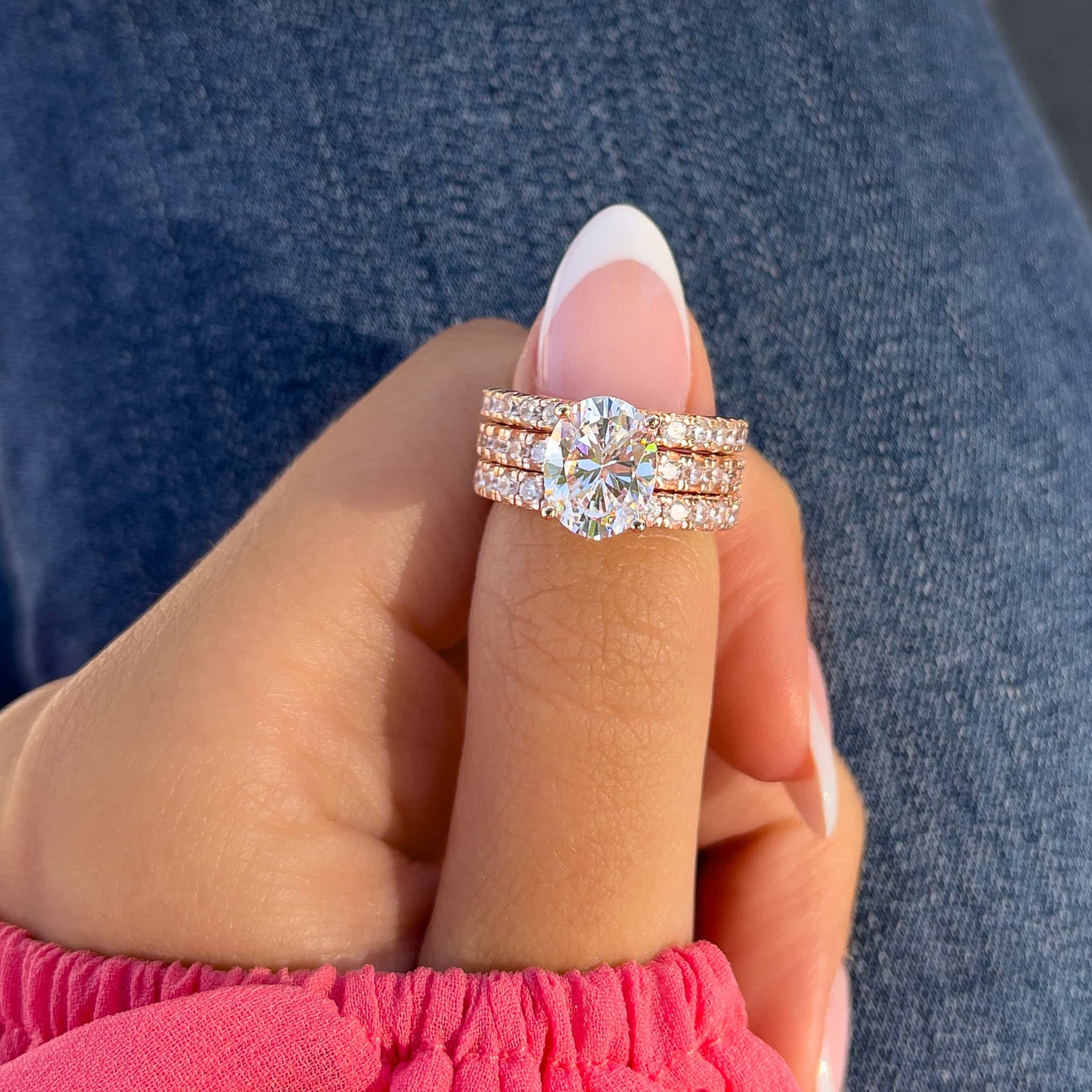 oval rose gold triple stack on female hand with pink sleeve and french tip nail