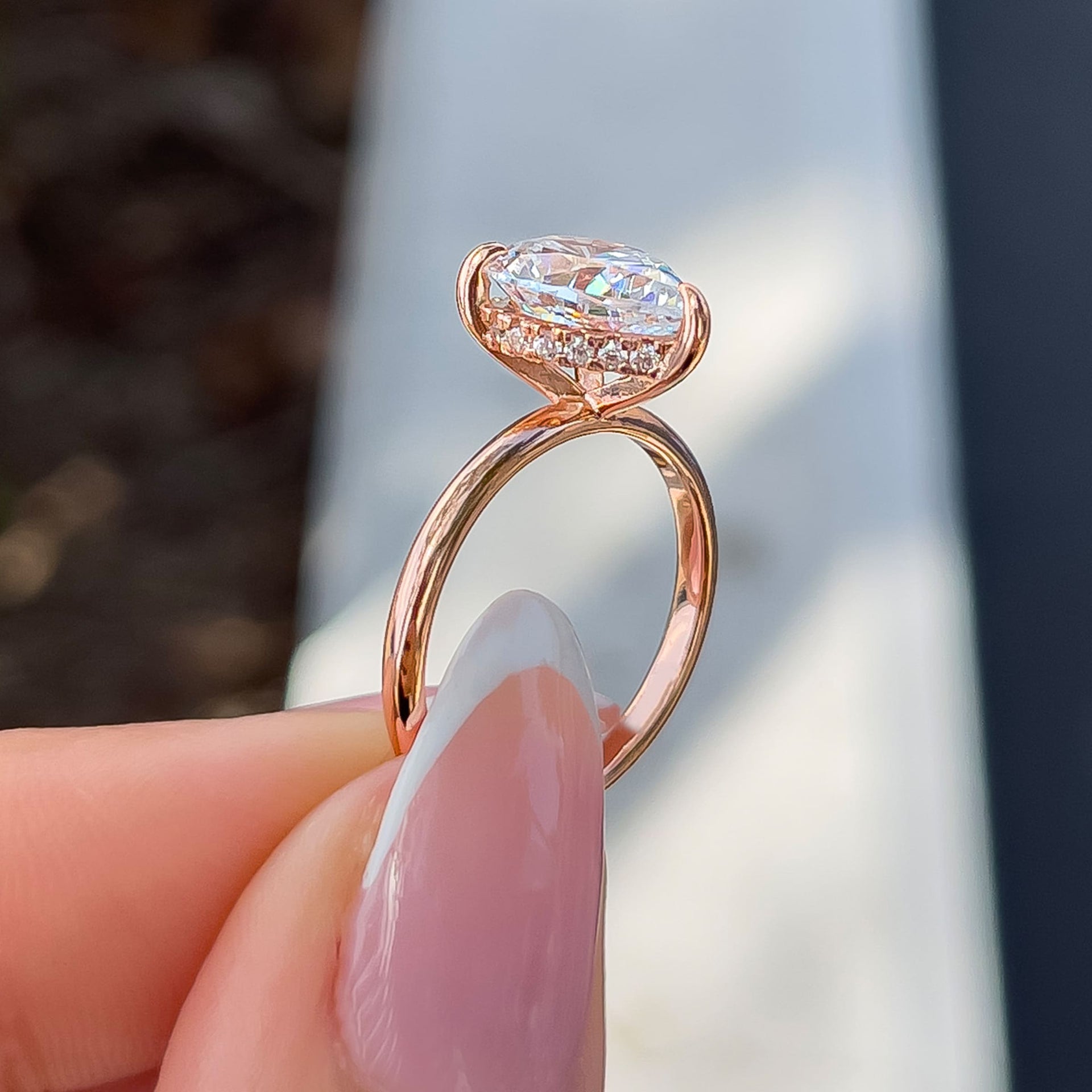 setting shot of a 3 carat rose gold pear cut solitaire engagement ring with a hidden halo detail