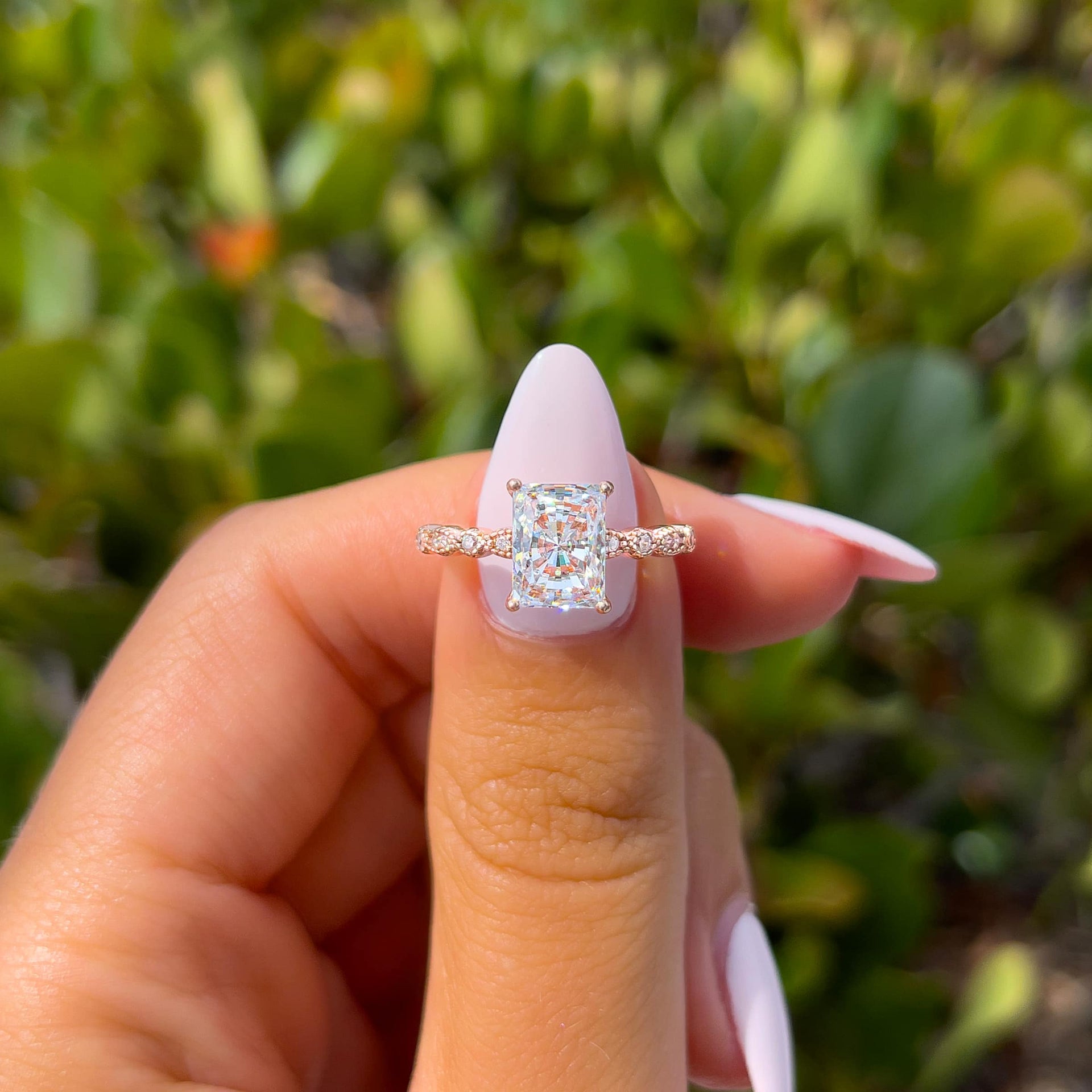 stunning rose gold radiant vintage style engagement ring held by model with light pink nails