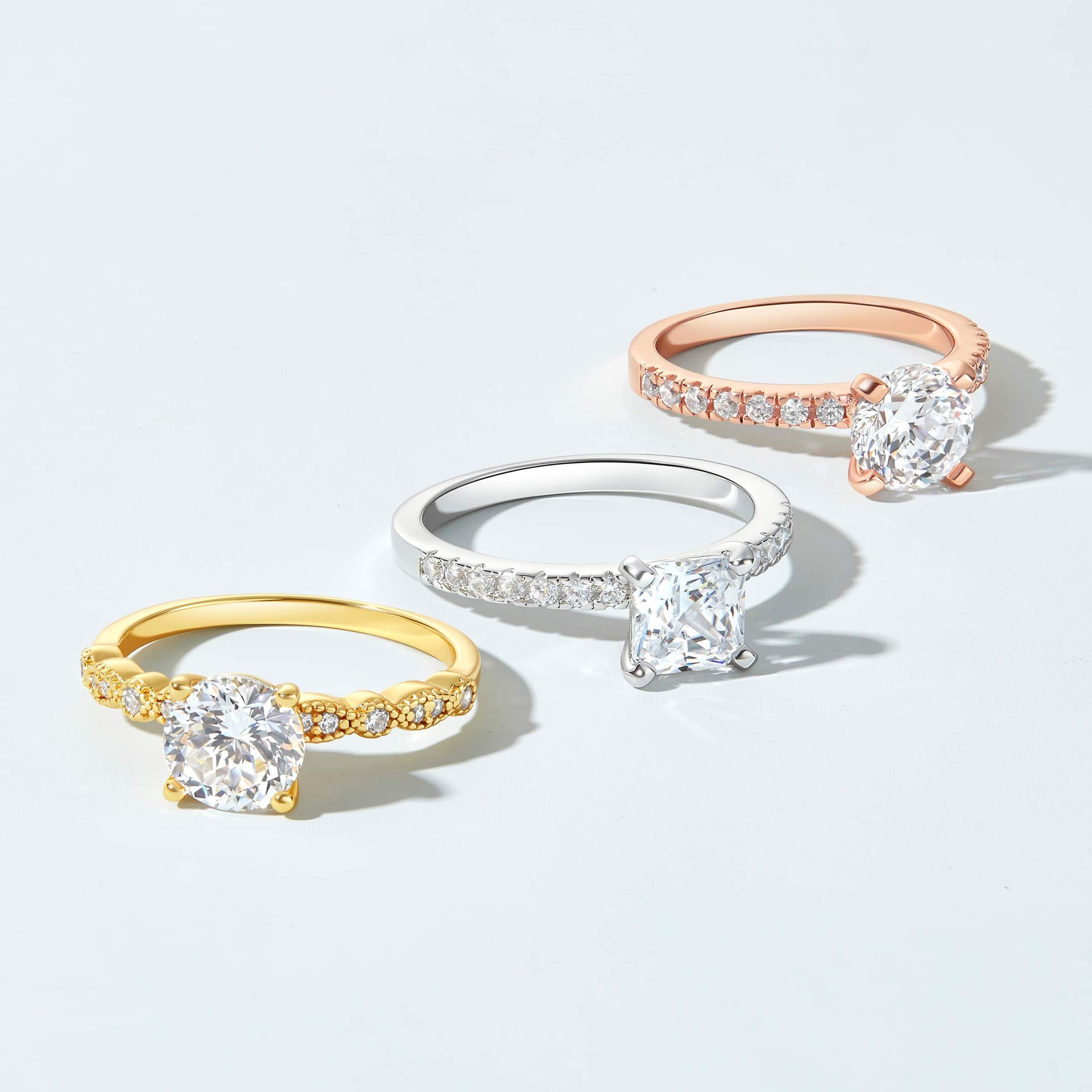 3 engagement rings in gold, silver, and rose gold all on an off-white background