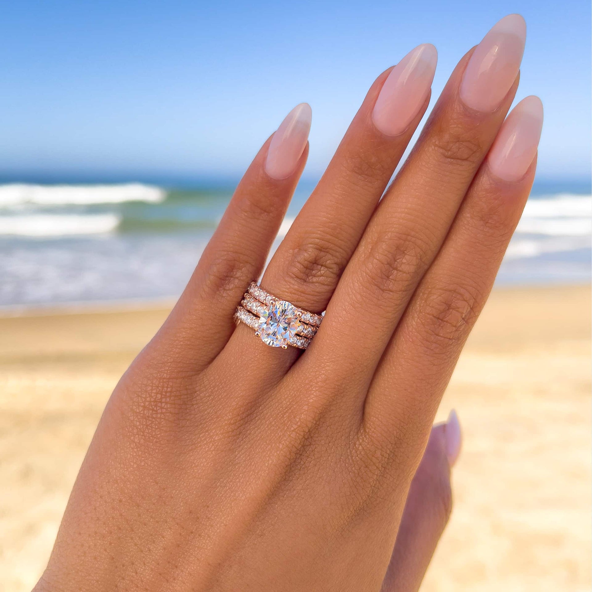 stunning oval cut engagement ring triple stack on female model at beach