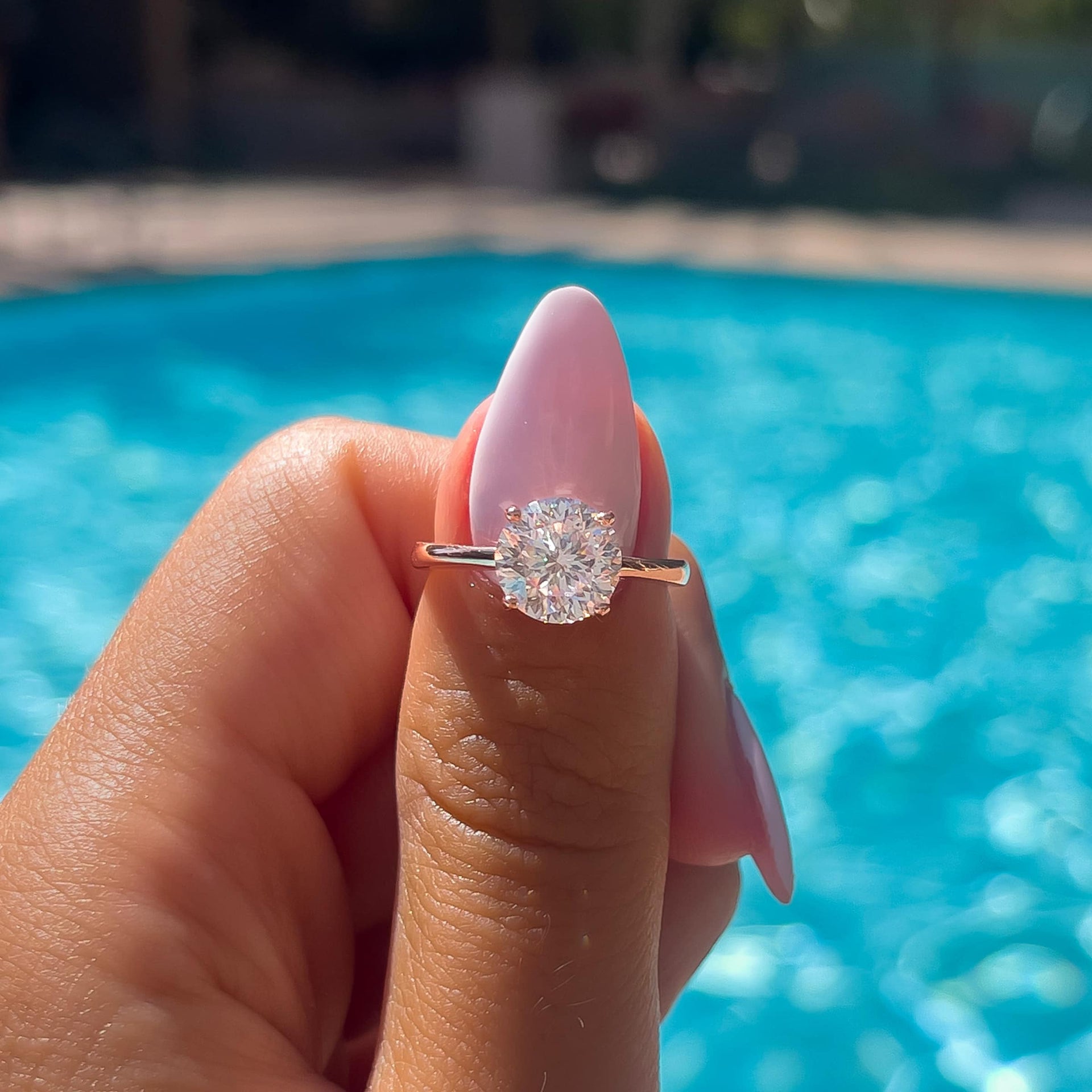 stunning 2 carat round cut solitaire engagement ring on model who is poolside