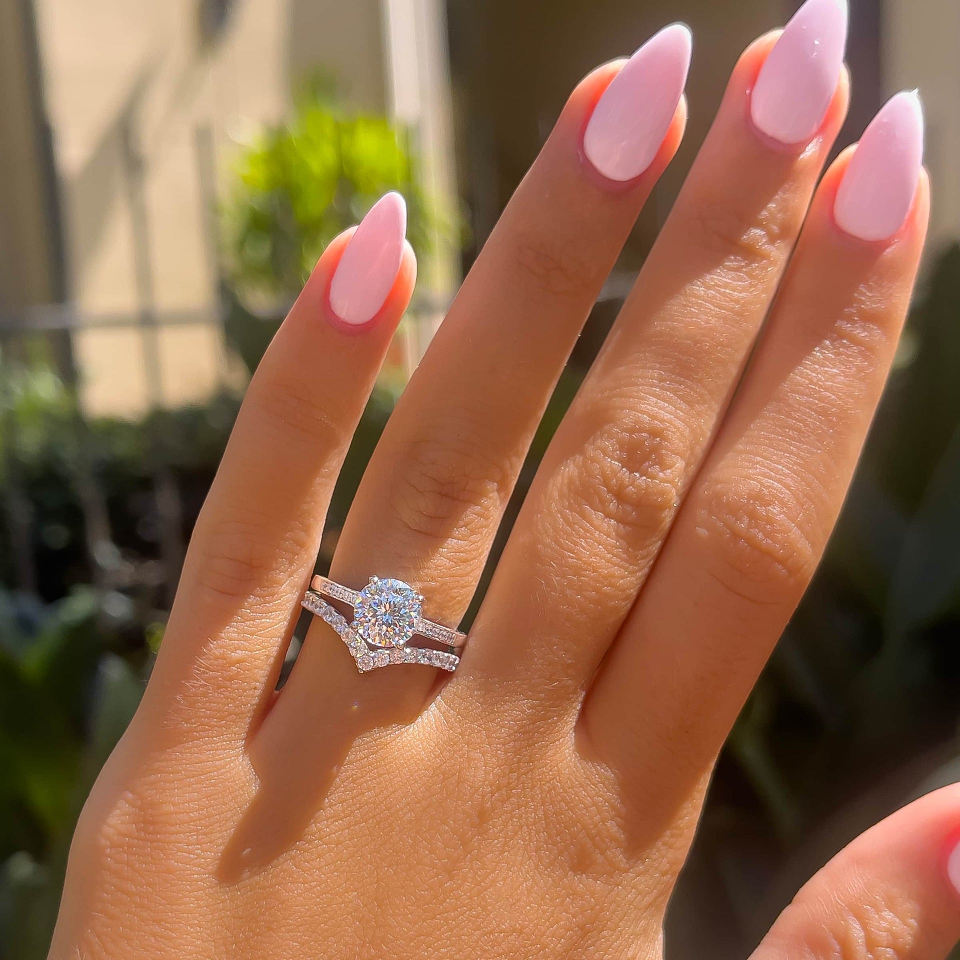 classic silver round cut engagement ring on model with light pink nails