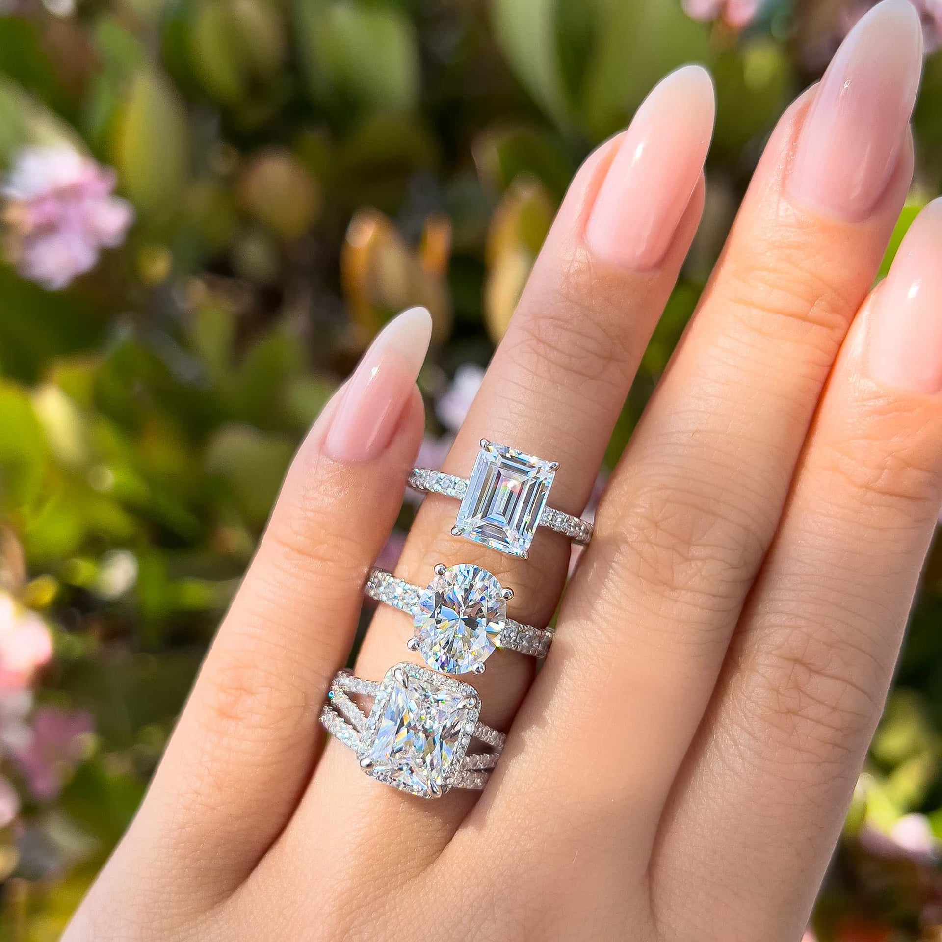 three stunning silver engagement rings modeled on female hand with neutral nails