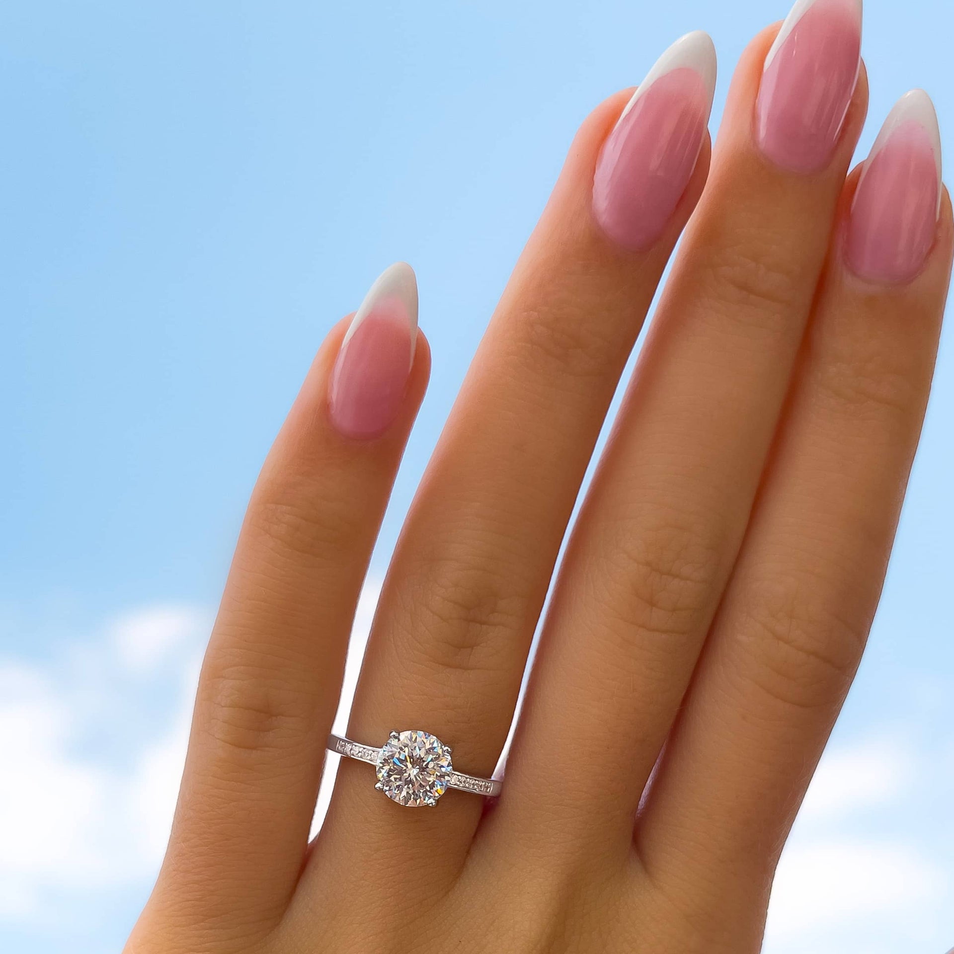 stunning round cut engagement ring on female hand with french tip nails