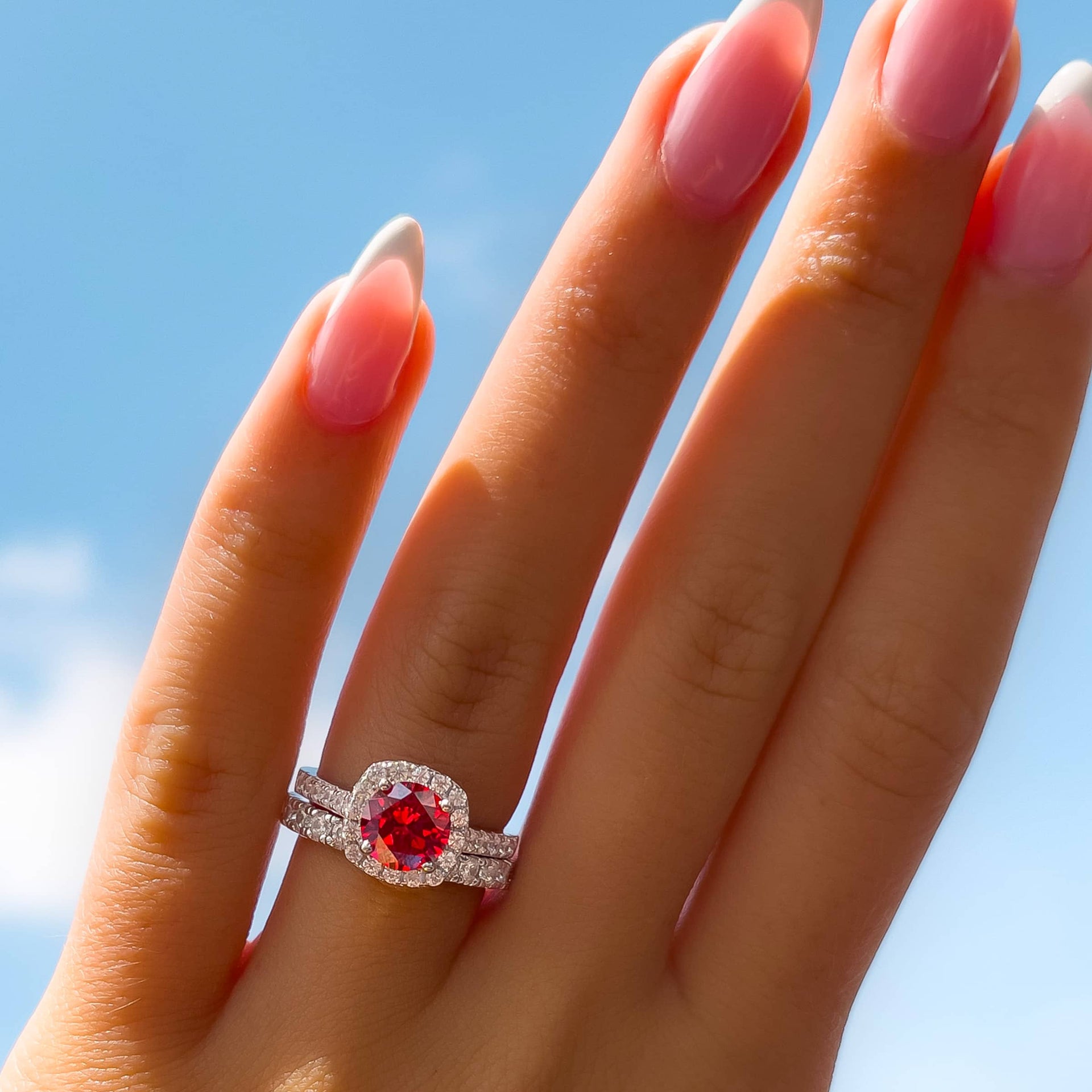 silver round cut ruby engagement ring paired with silver wedding band on female hand