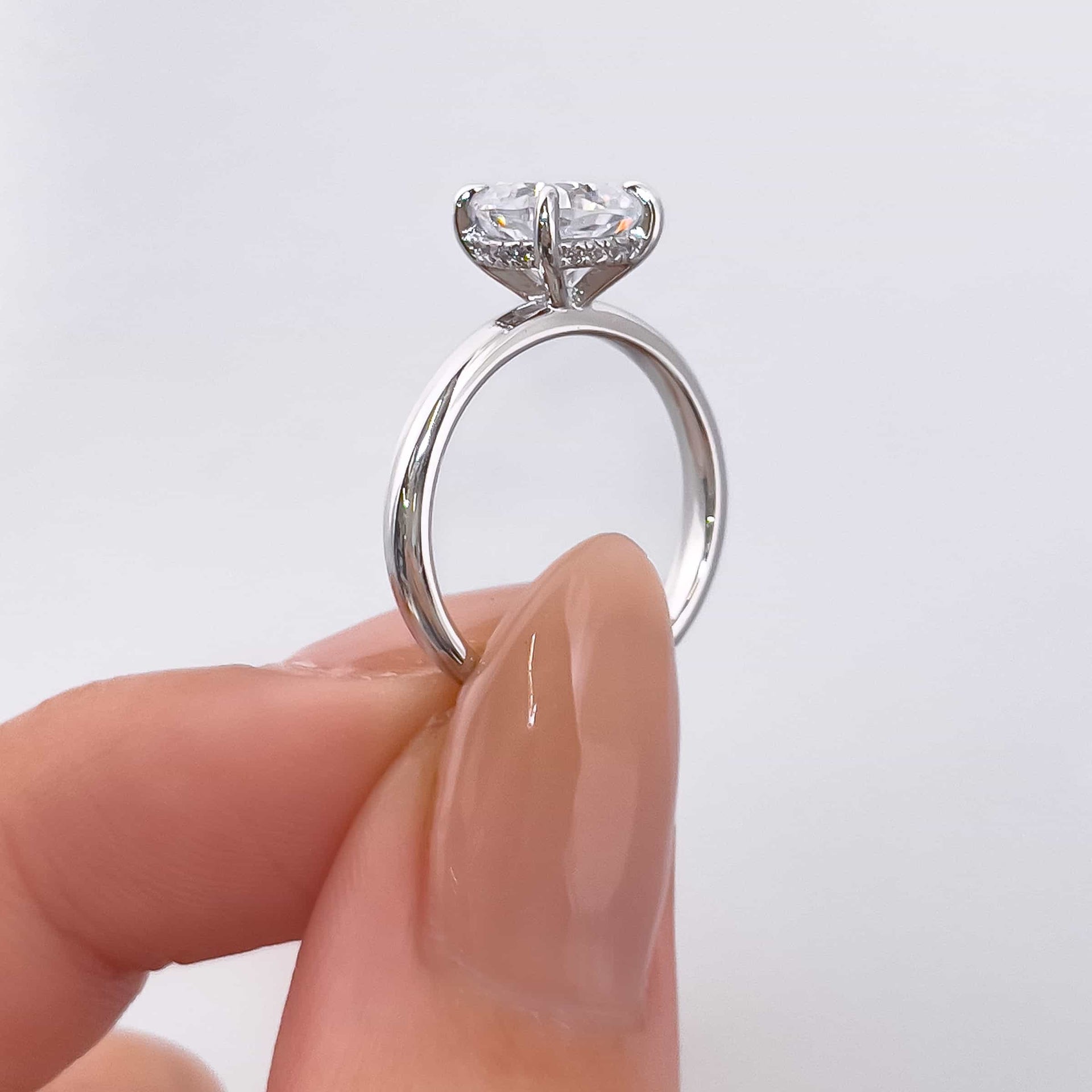 side profile of 1.5 carat cushion cut engagement ring with hidden halo detail on model with neutral tan nails