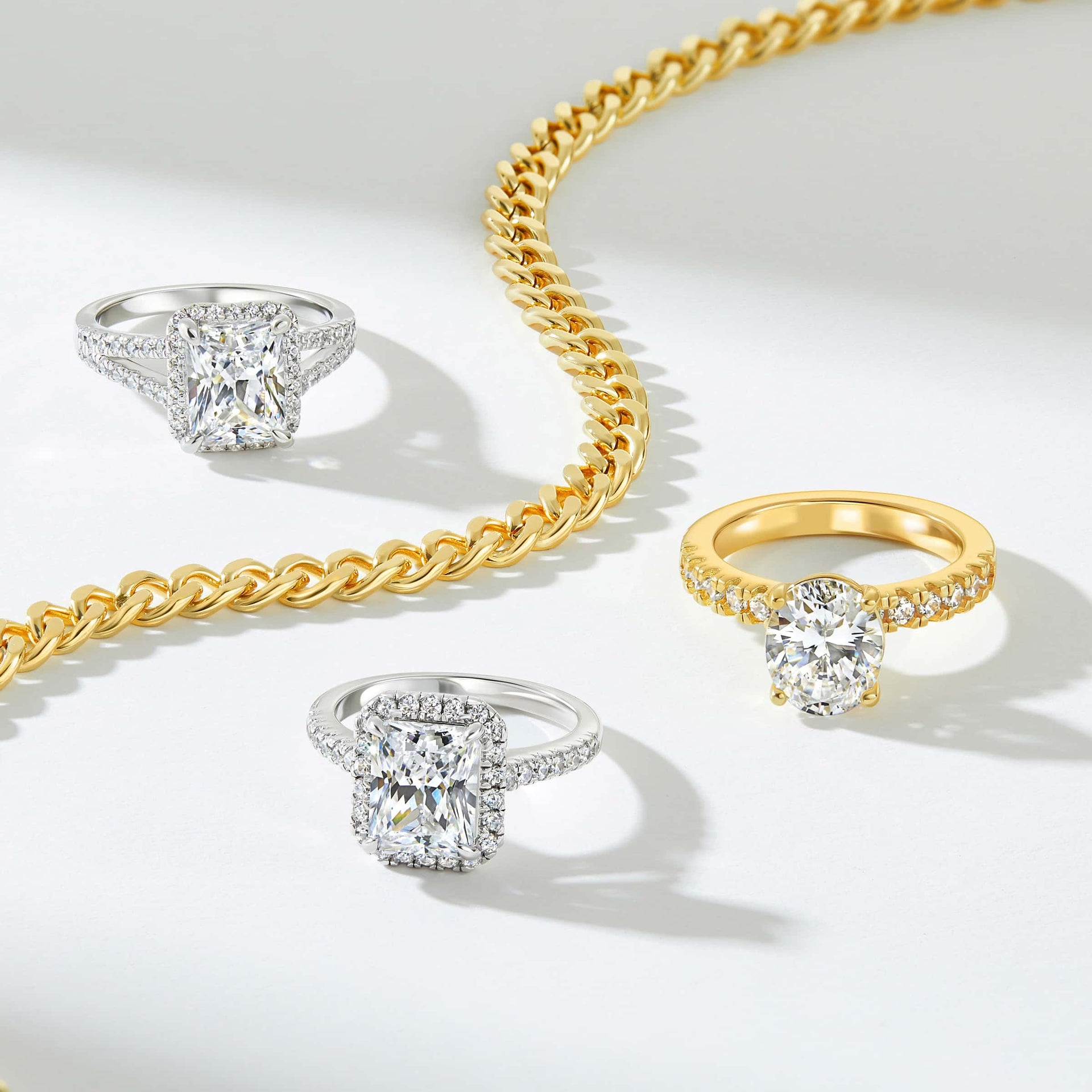 stunning engagement rings in silver and gold with a gold chain along the middle of them all