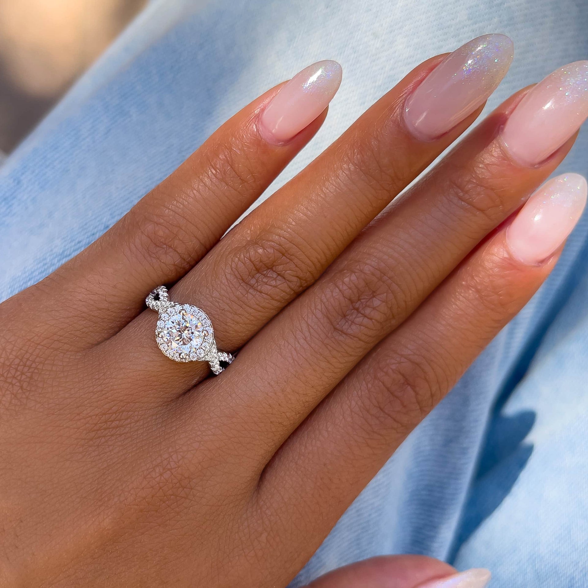 vintage round cut halo engagement ring on model with neutral almond nails