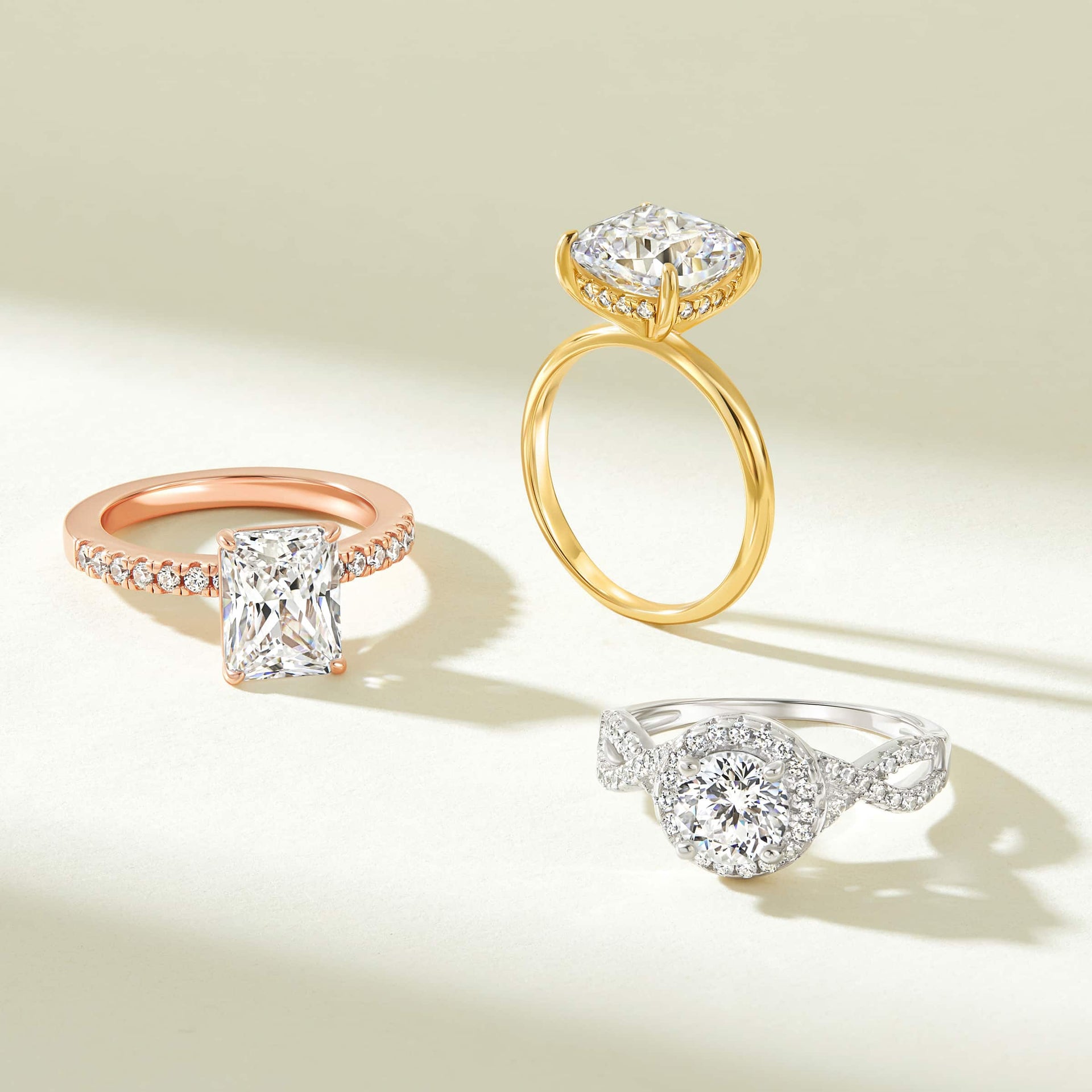 A rose gold, gold, and silver engagement ring all shown on a tan background