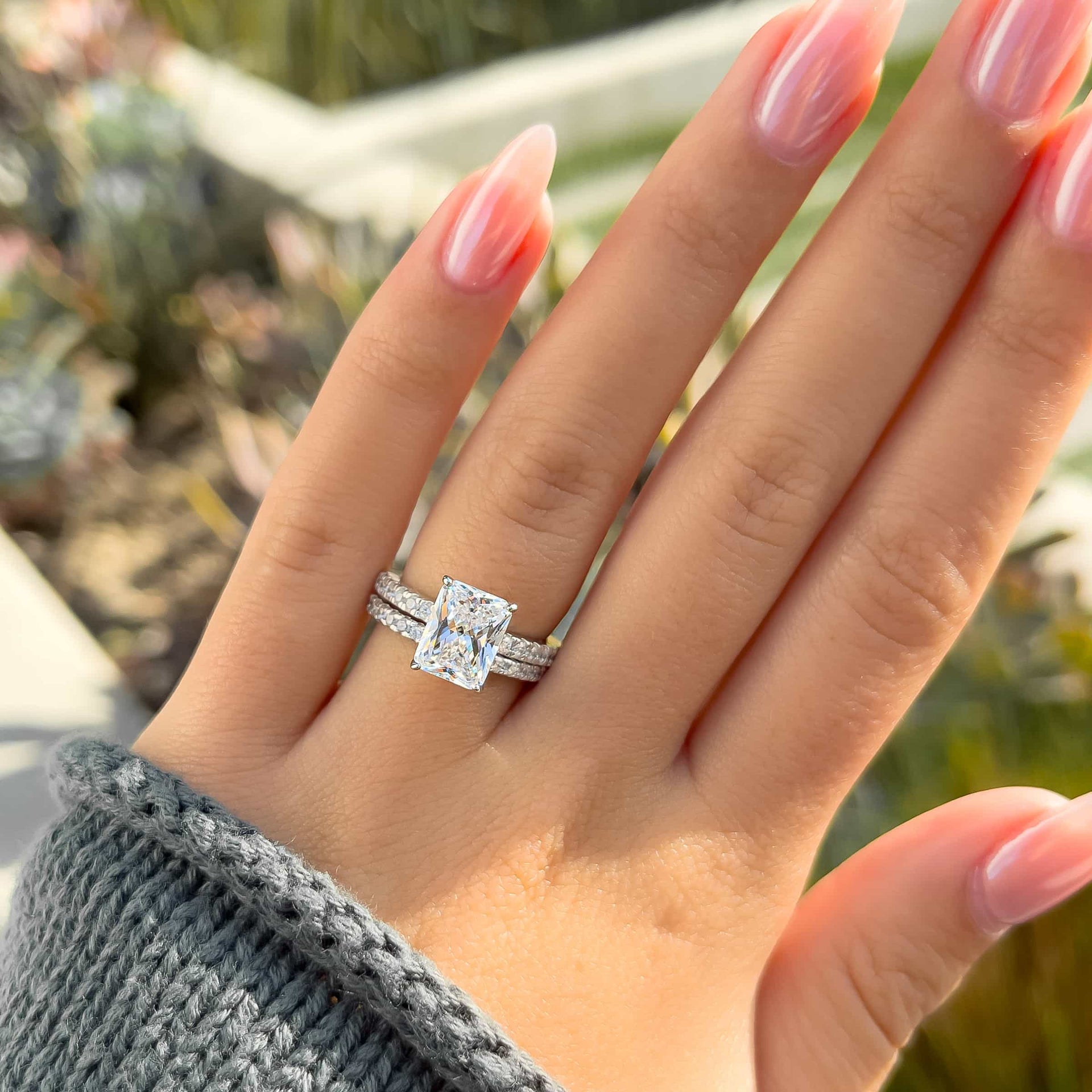 simple silver radiant cut wedding ring set on model with neutral nails and sweater