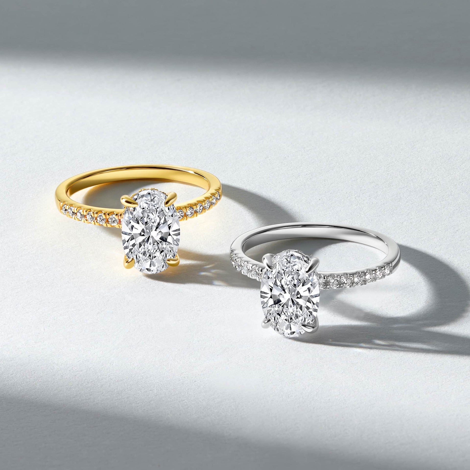 a 4 carat oval cut half eternity engagement ring shown in gold and silver on a textured off white background