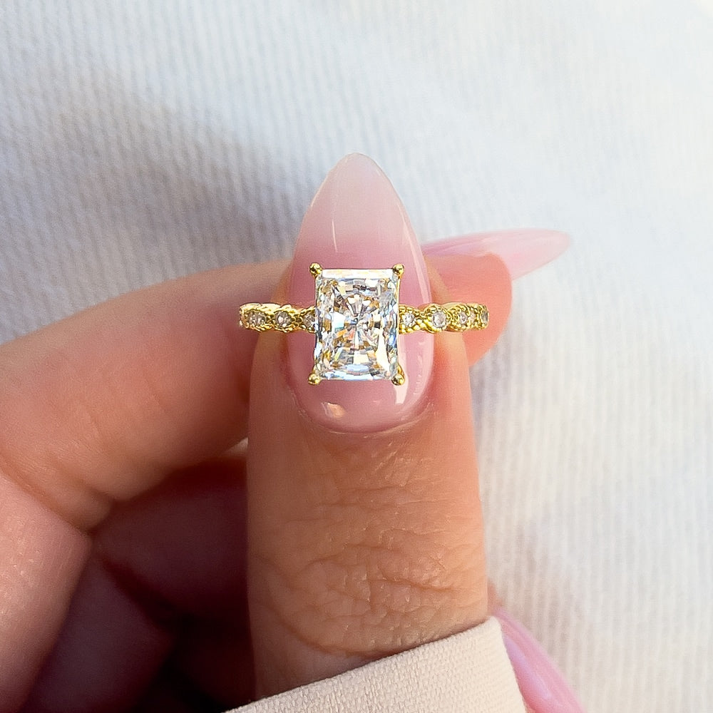 stunning gold radiant cut engagement ring on model's thumb