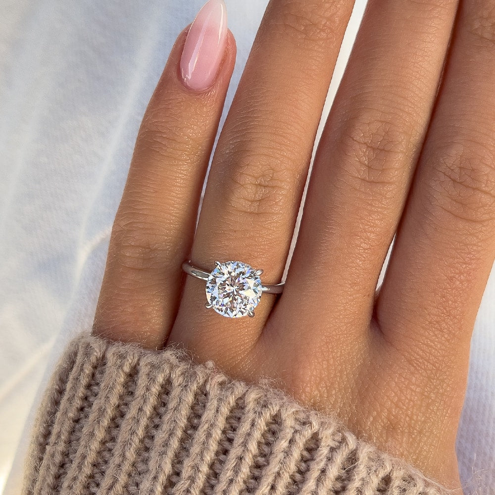 stunning silver solitaire engagement ring on model's hand with pink nails