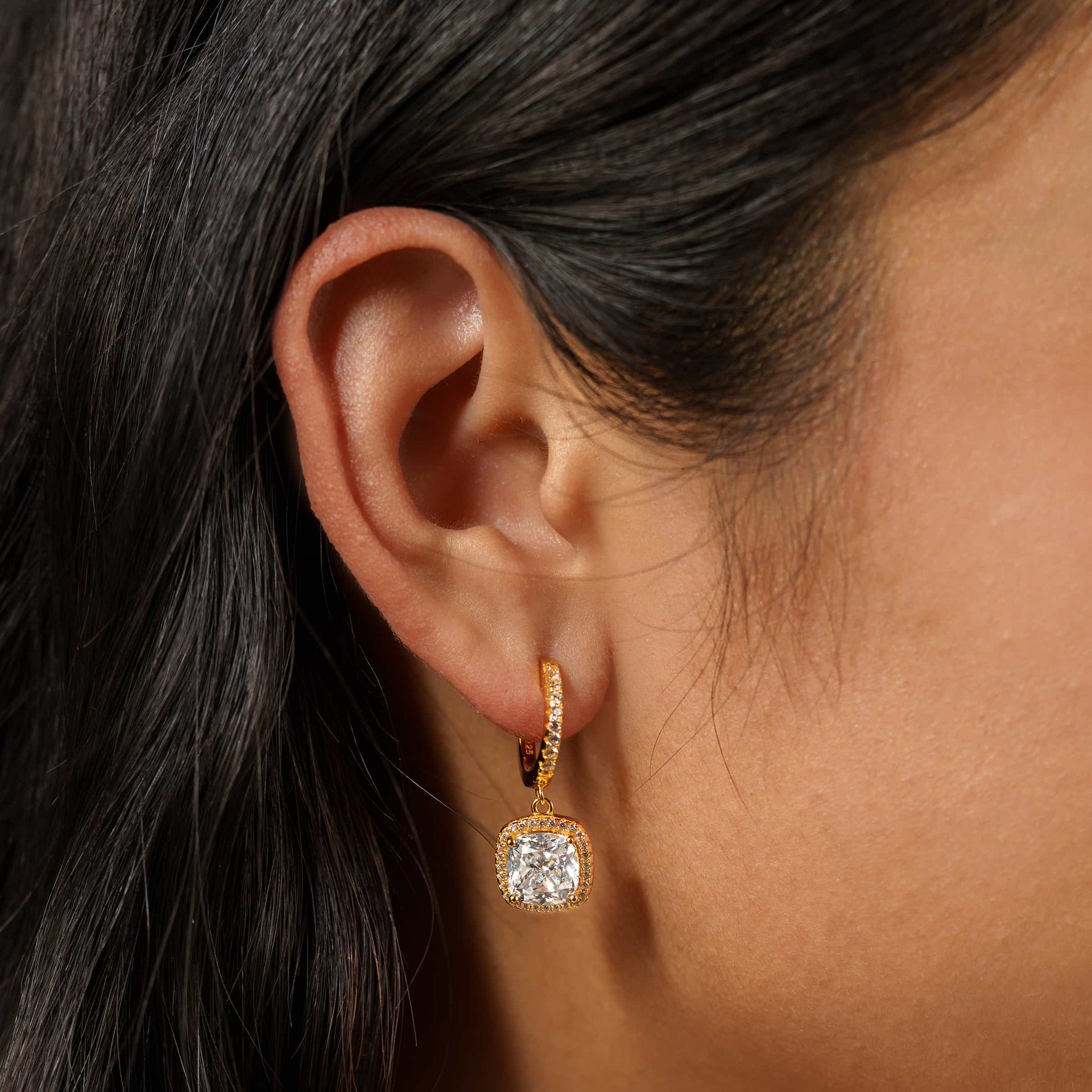 bold, gold cushion cut halo pendant dangling hoop earrings on model