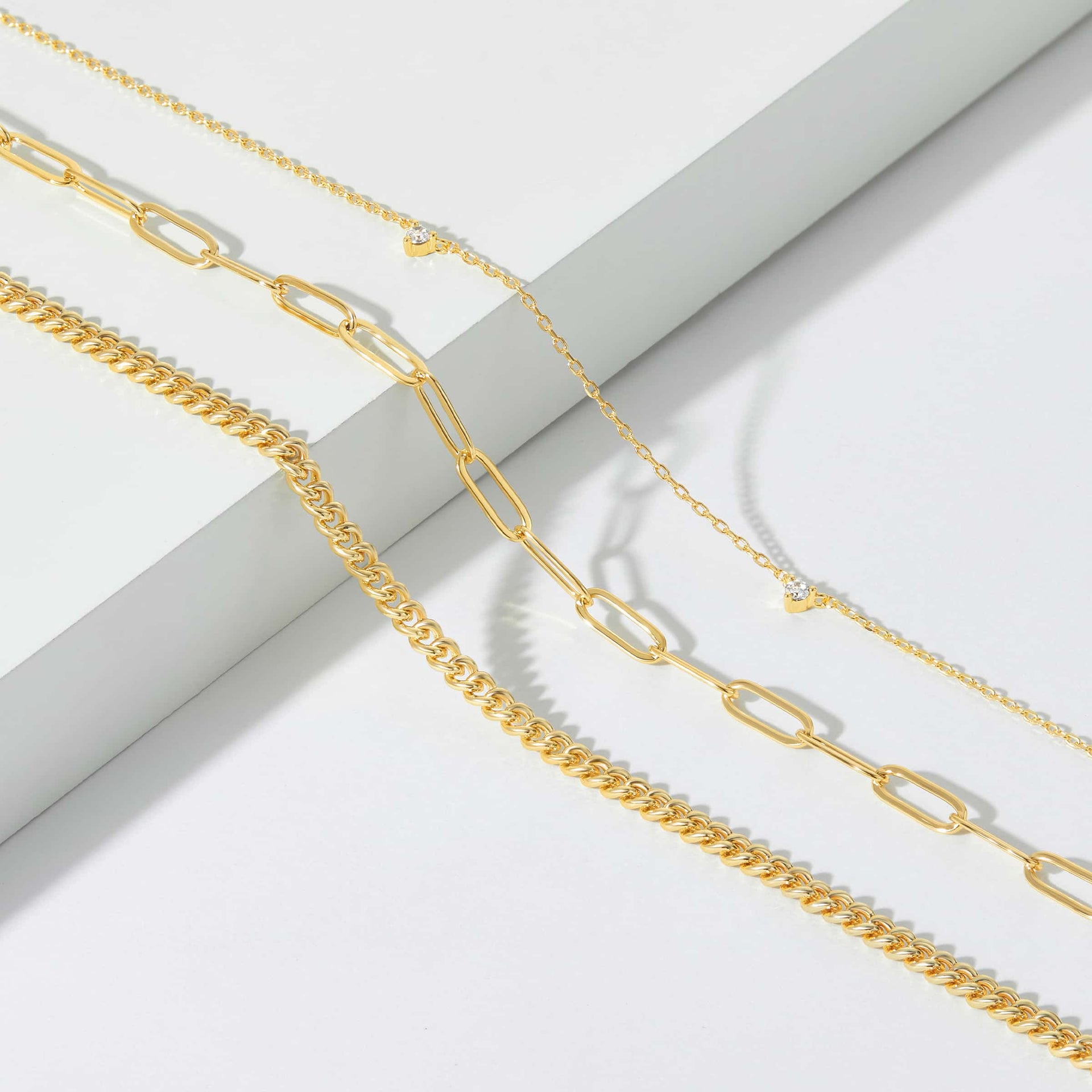 three beautiful gold necklaces on white backdrop