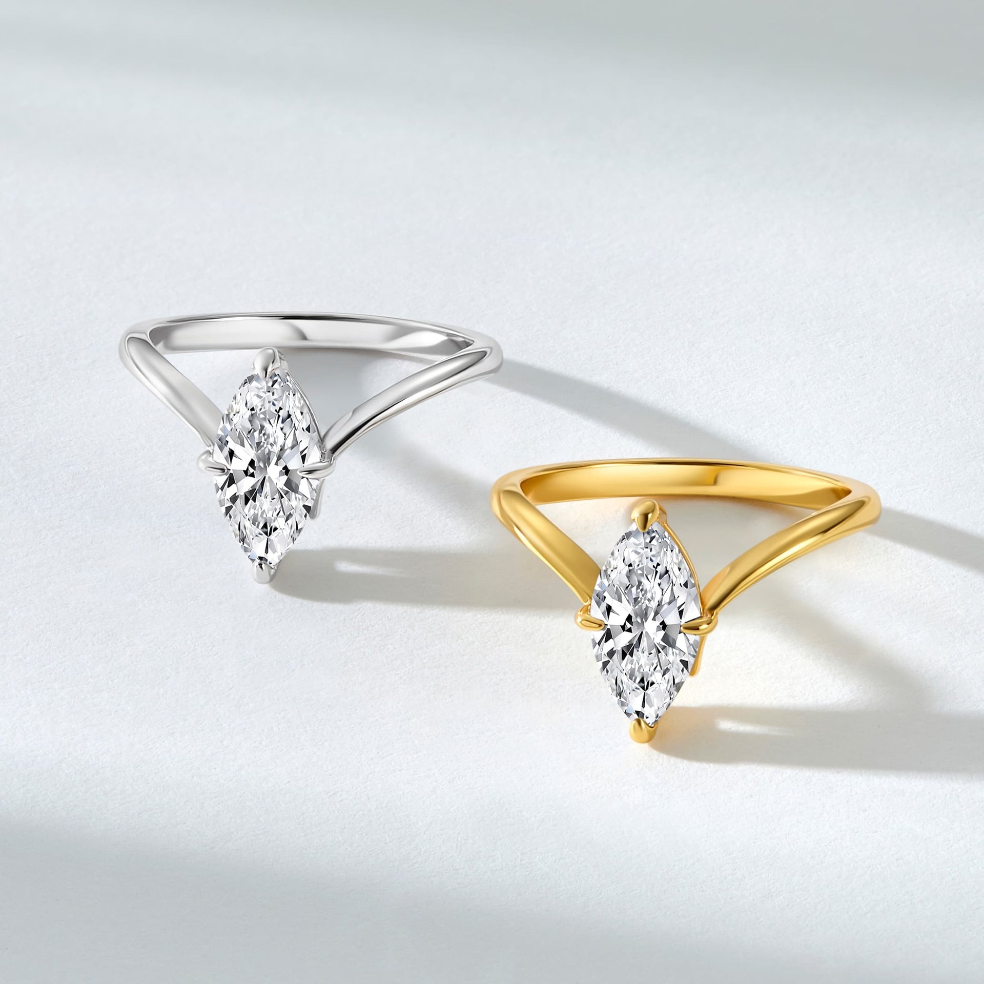 a 2 carat marquise solitaire chevron engagement ring shown in silver and gold on a textured white background