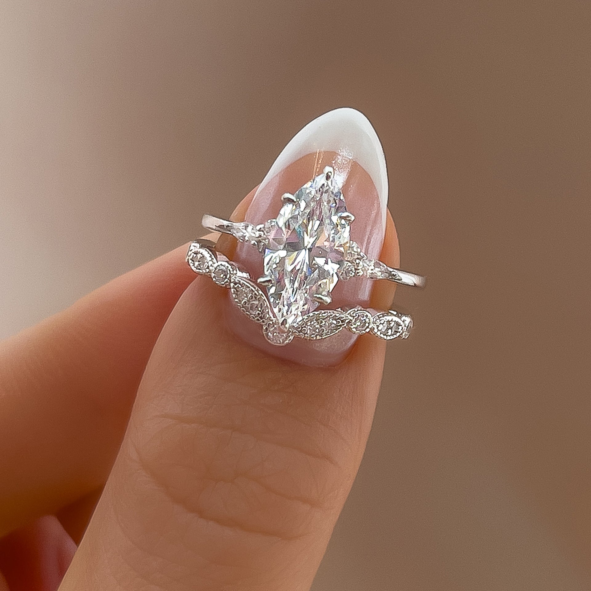 stunning marquise engagement ring shown with chevron wedding band on model's manicured thumb